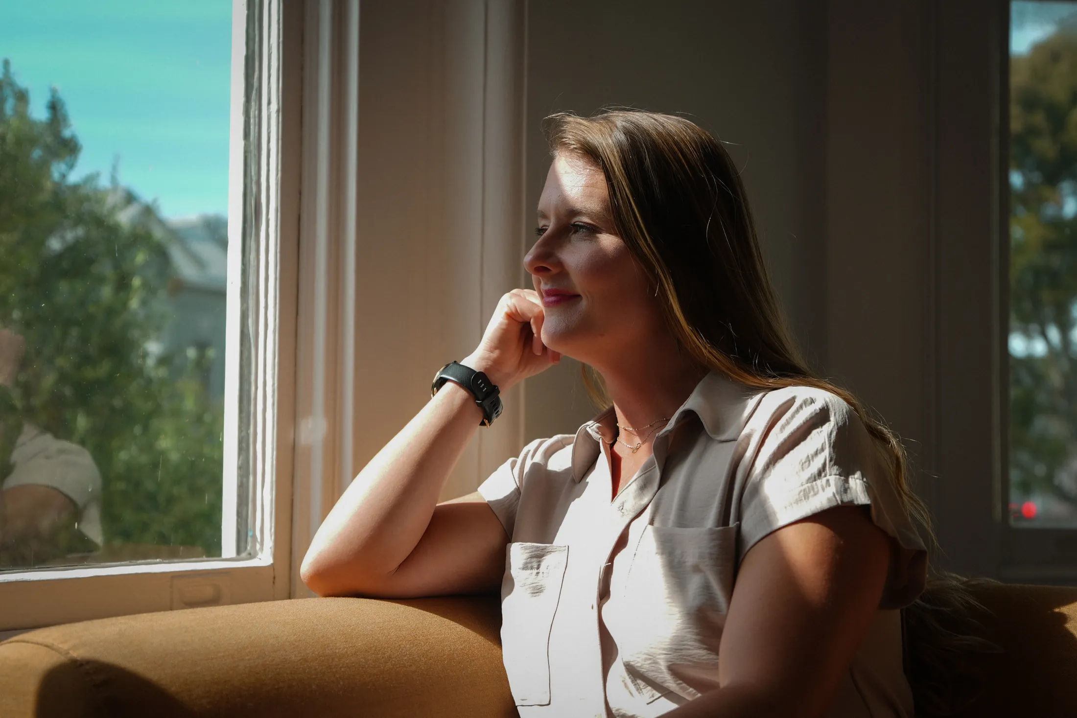 Carissa resting her chin on her hand by a sunlit window