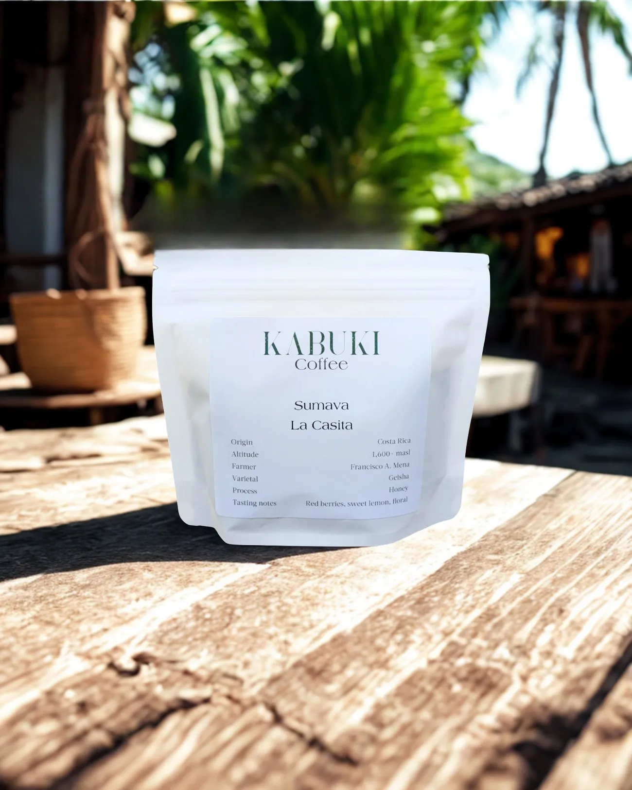 Un sachet de café Kabuki blanc étiqueté Sumava La Casita posé sur une table en bois, avec un fond rustique et de la verdure floue