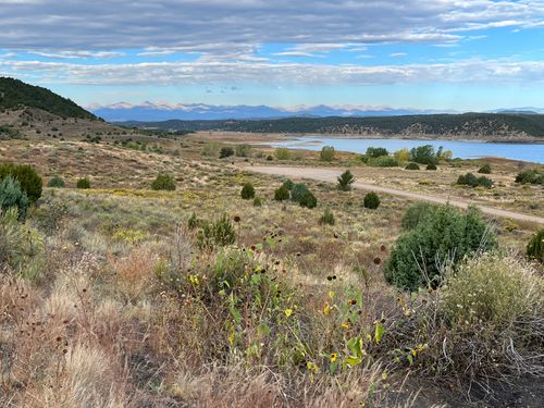 A view of the distant Sangre de Cristo mountains looking over fall colors and Trinidad Lake.
