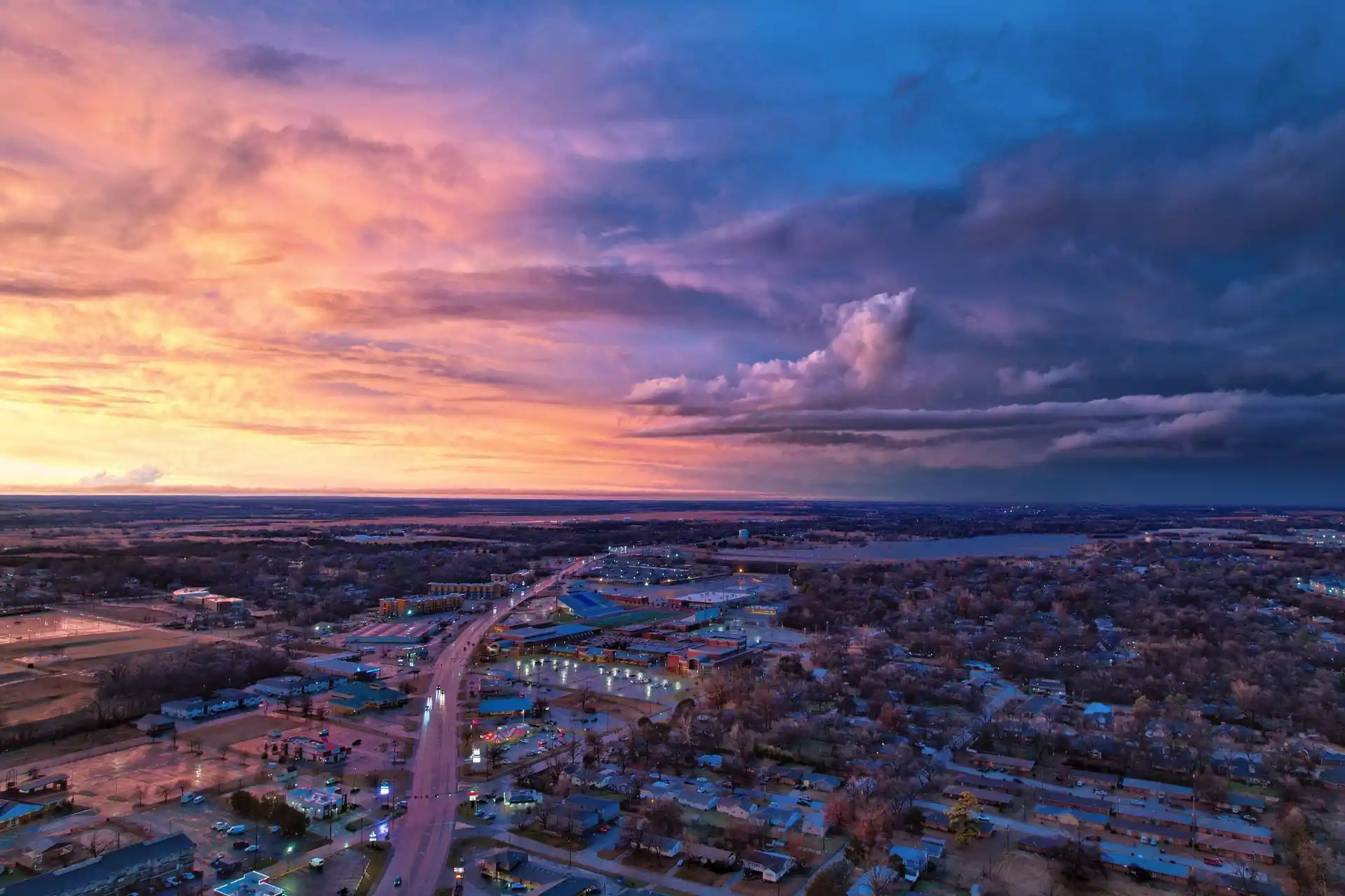 Aerial view of a small town under a colorful sunset sky