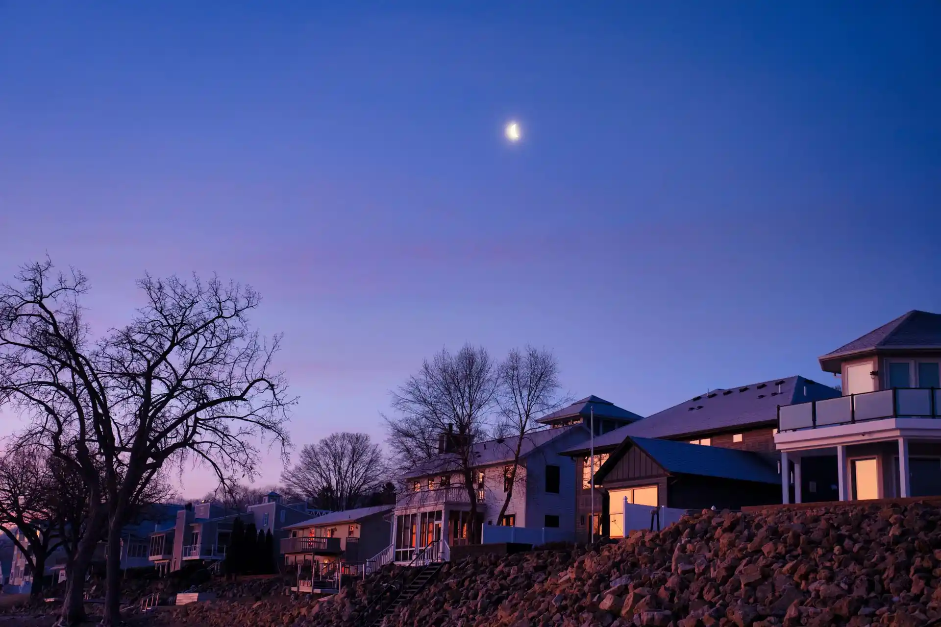 Waterfront homes on a rocky shoreline at dusk