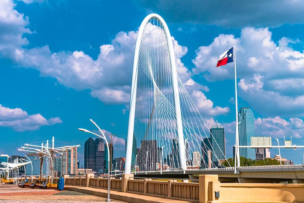Margaret Hunt Hill Bridge and the Dallas skyline with a Texas flag