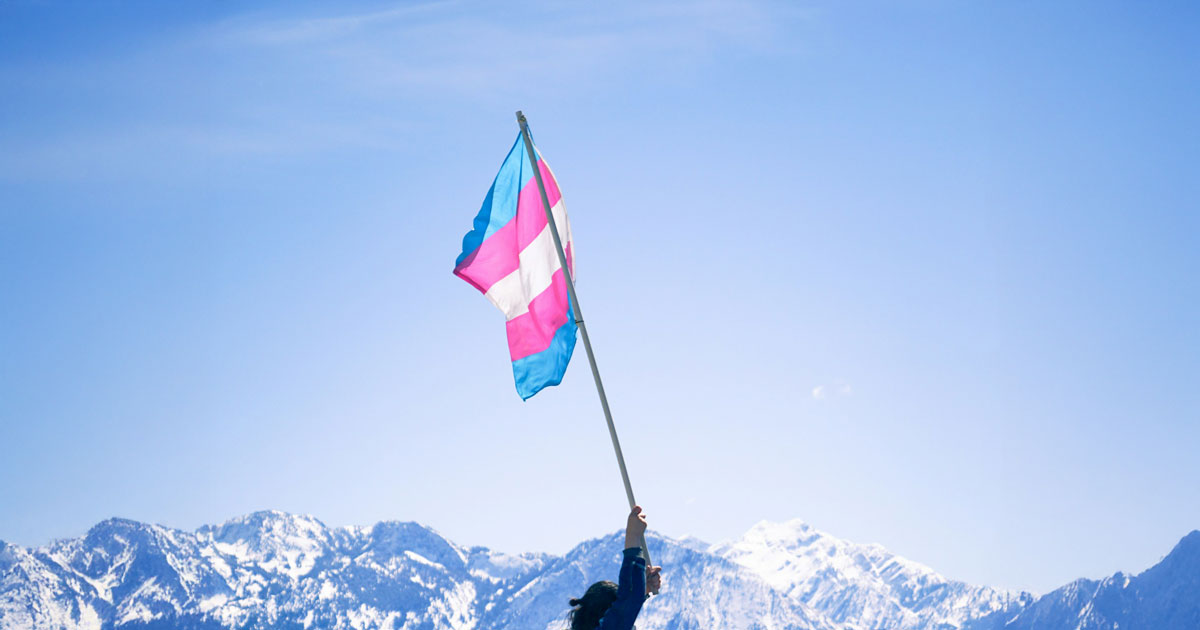 Trans flag waving with mountains in the background