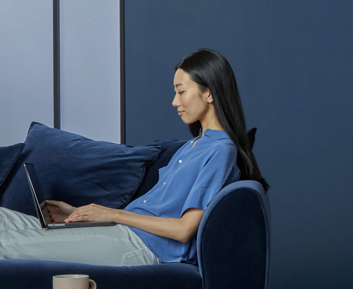 A woman sitting on a couch using a laptop computer