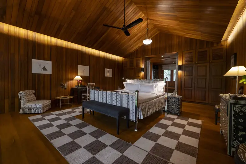 A timber-panelled bedroom with a checked rug and a softly lit sloping ceiling.