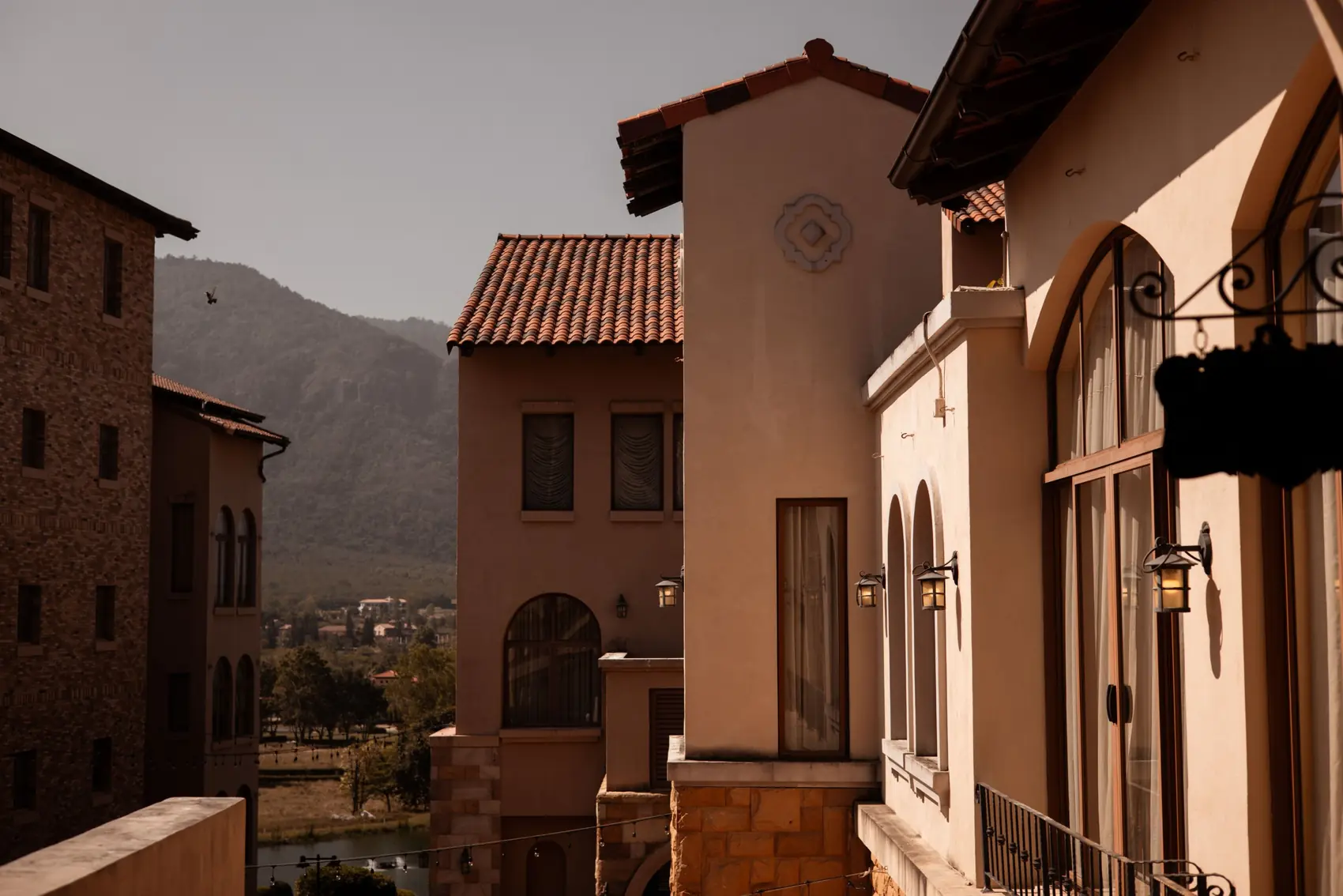 Terracotta roofs, arched windows and lanterns, with the mountain behind.