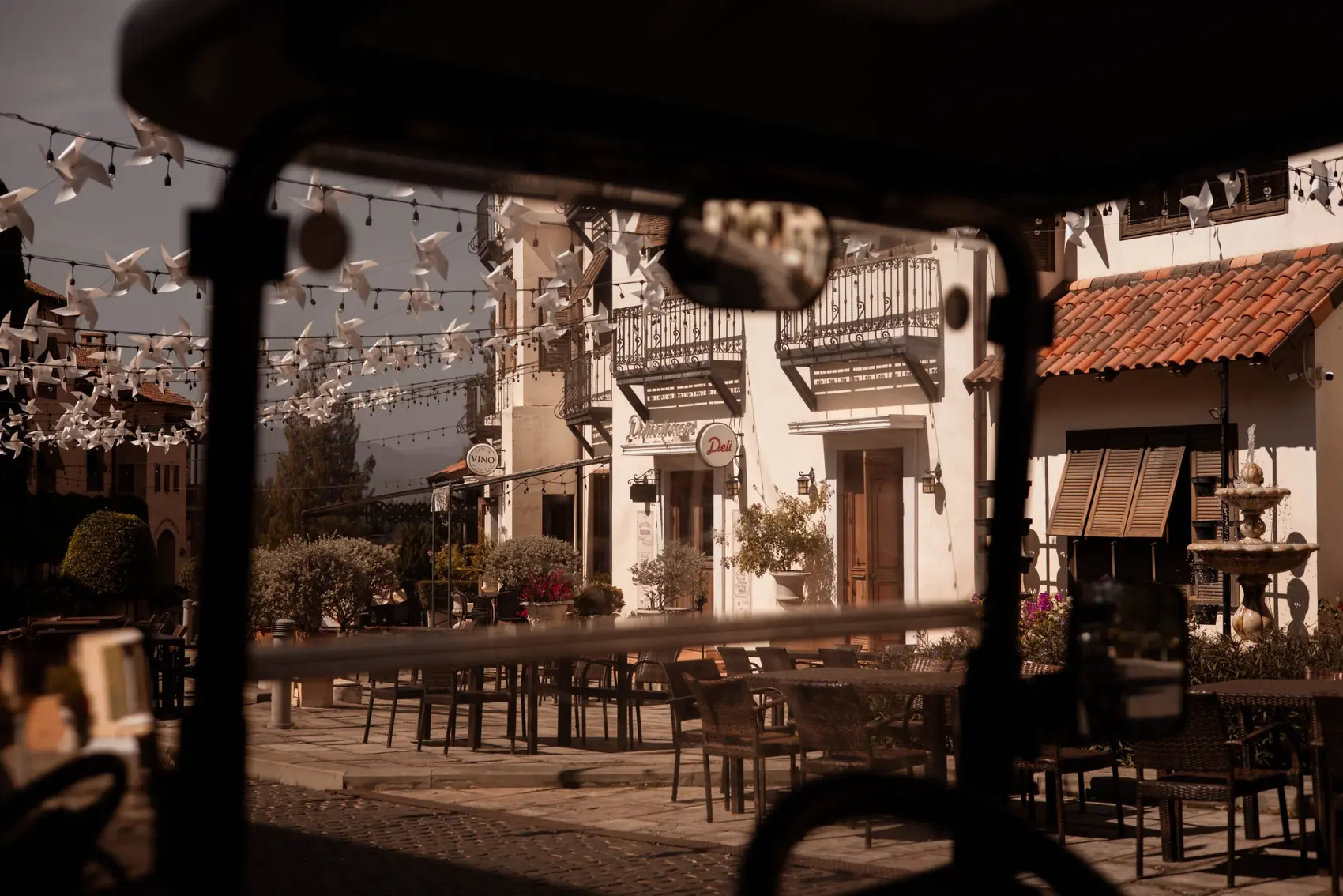 Town Square seen through the windscreen of a buggy, with pinwheels strung above the terrace.