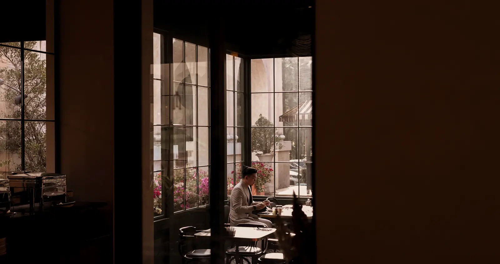 A guest breakfasting alone at a window table, with flowering bougainvillea outside.