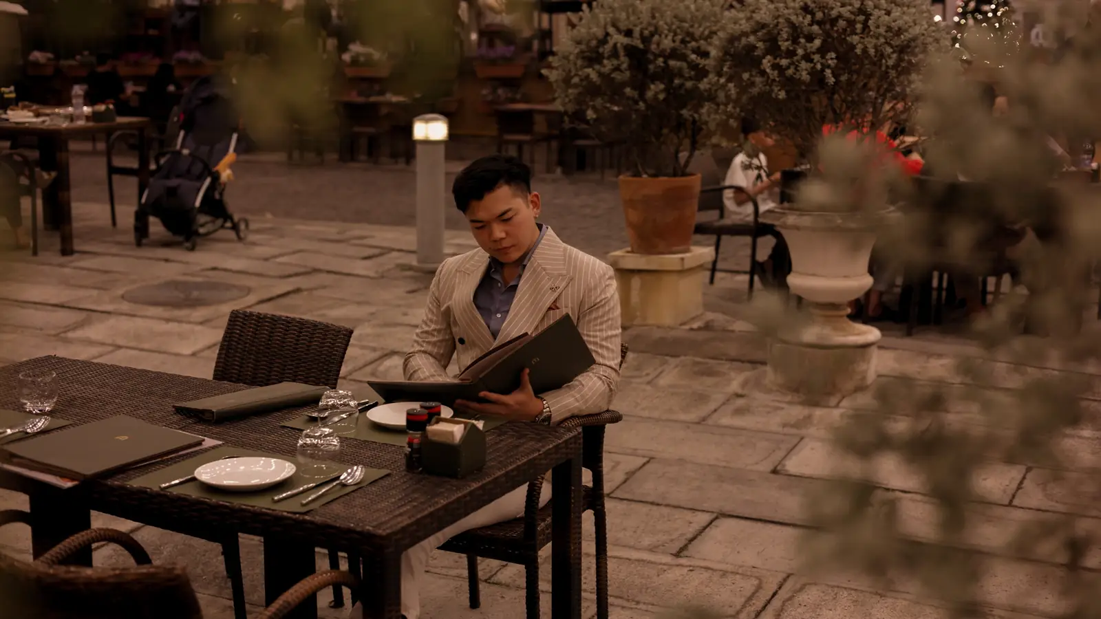 A guest reading the menu at a café table on the piazza.