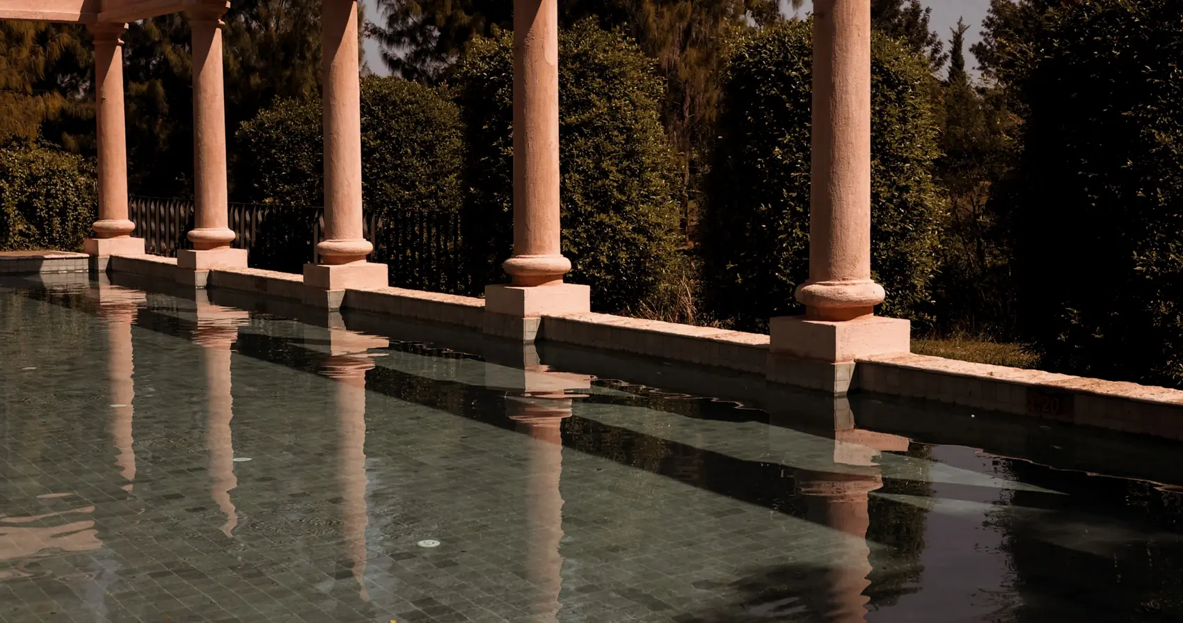 Stone columns reflected in the still water of the pool.