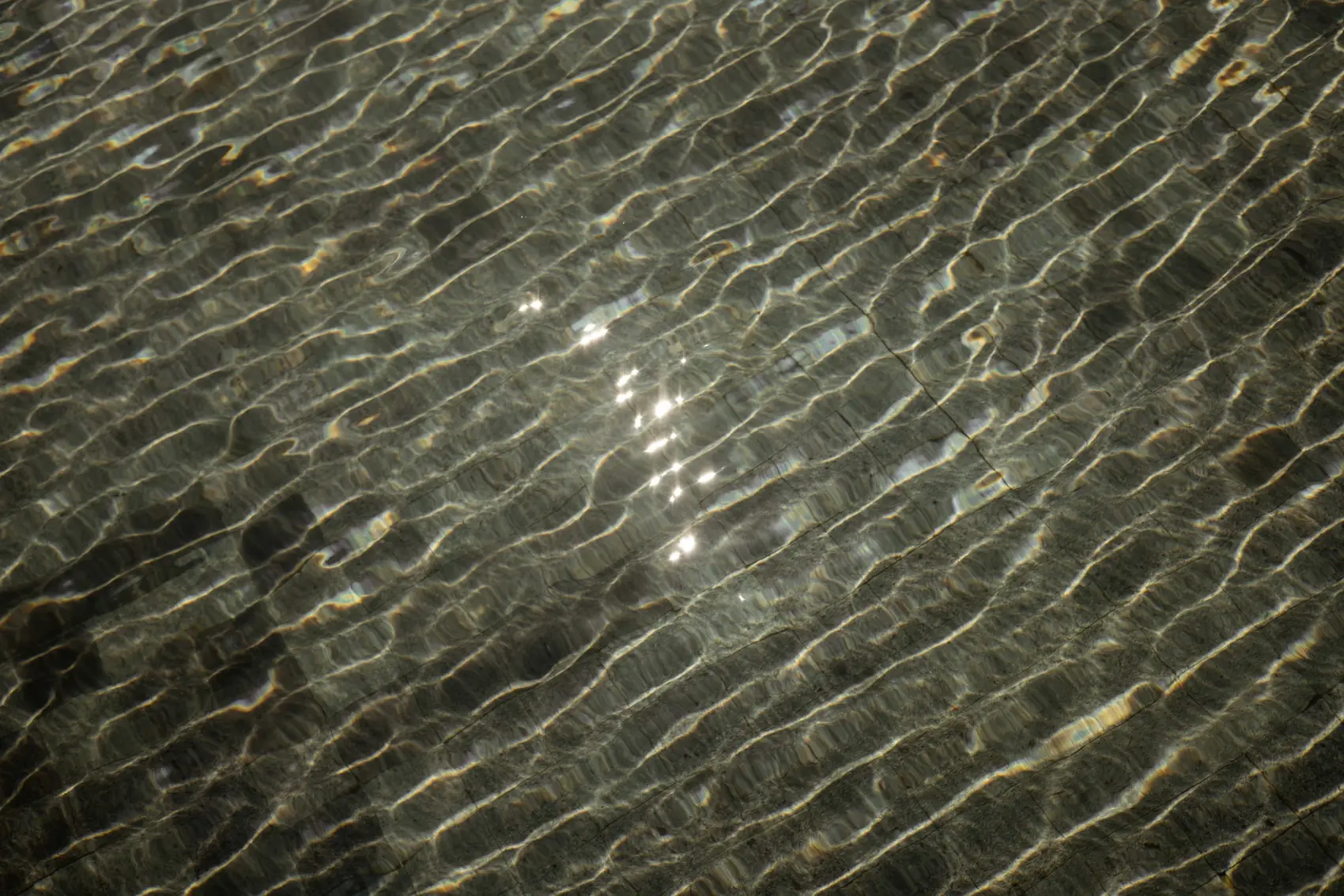 Sunlight on rippling water over tile.
