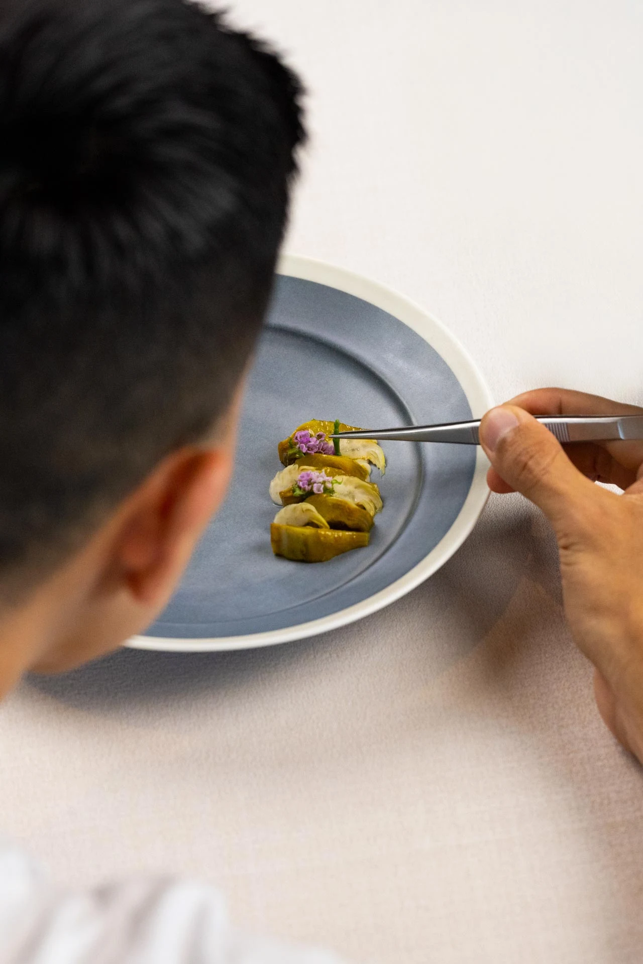A chef carefully finishing a plated dish at BLUE.