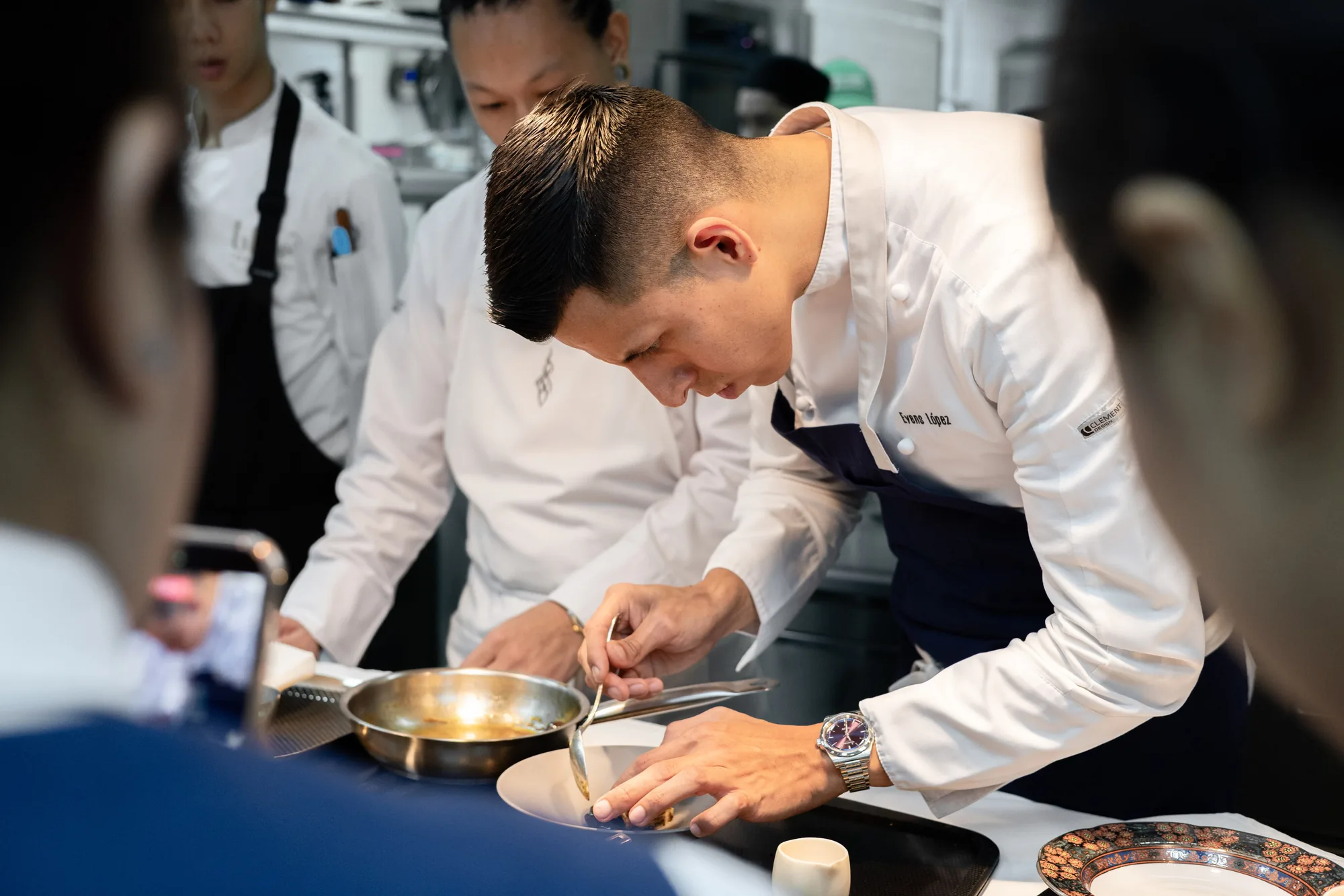 The BLUE and AKKEE chefs finishing a dish together at the pass.