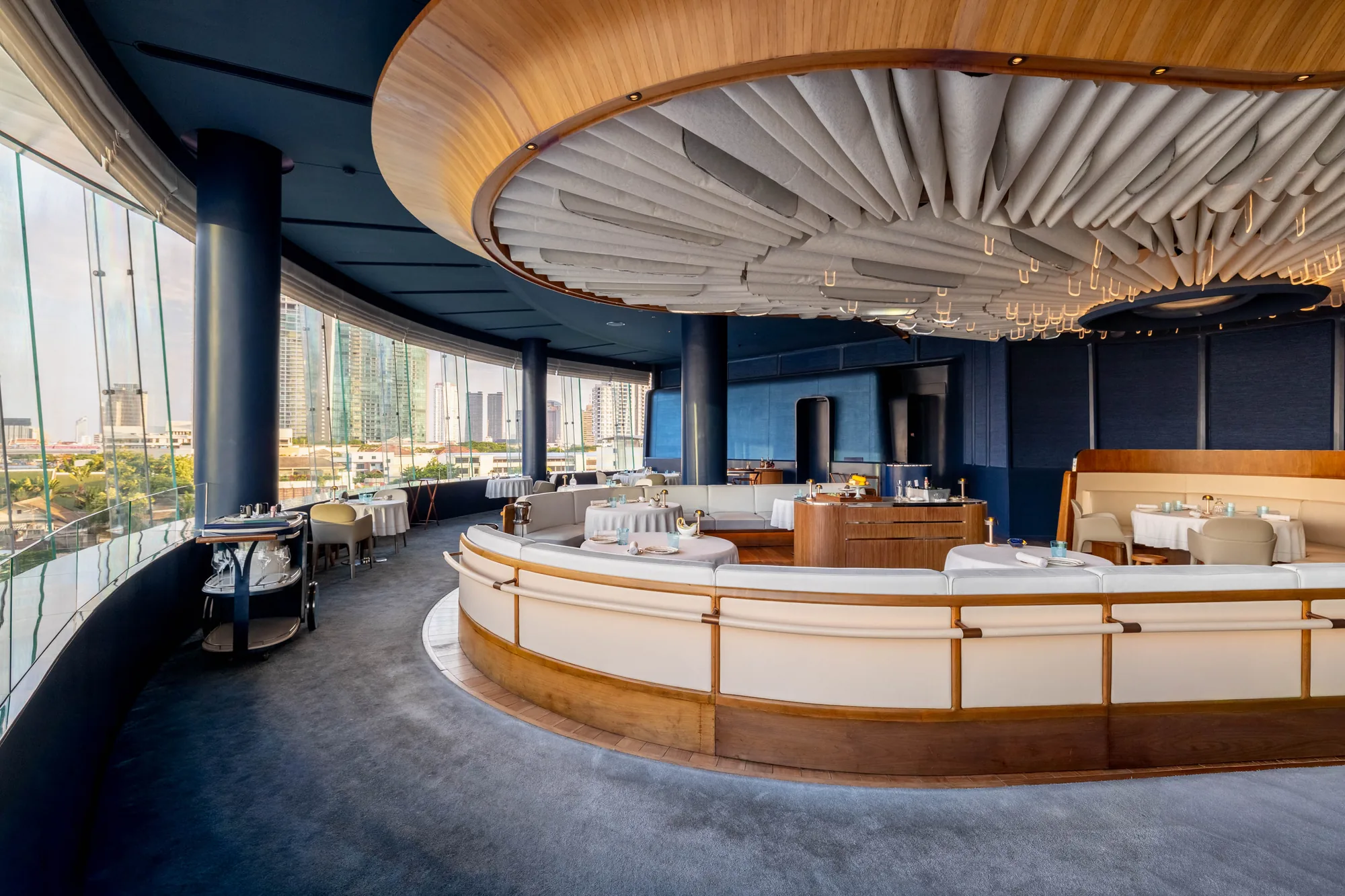 BLUE’s curved dining room beneath the sculptural ceiling, overlooking Bangkok.