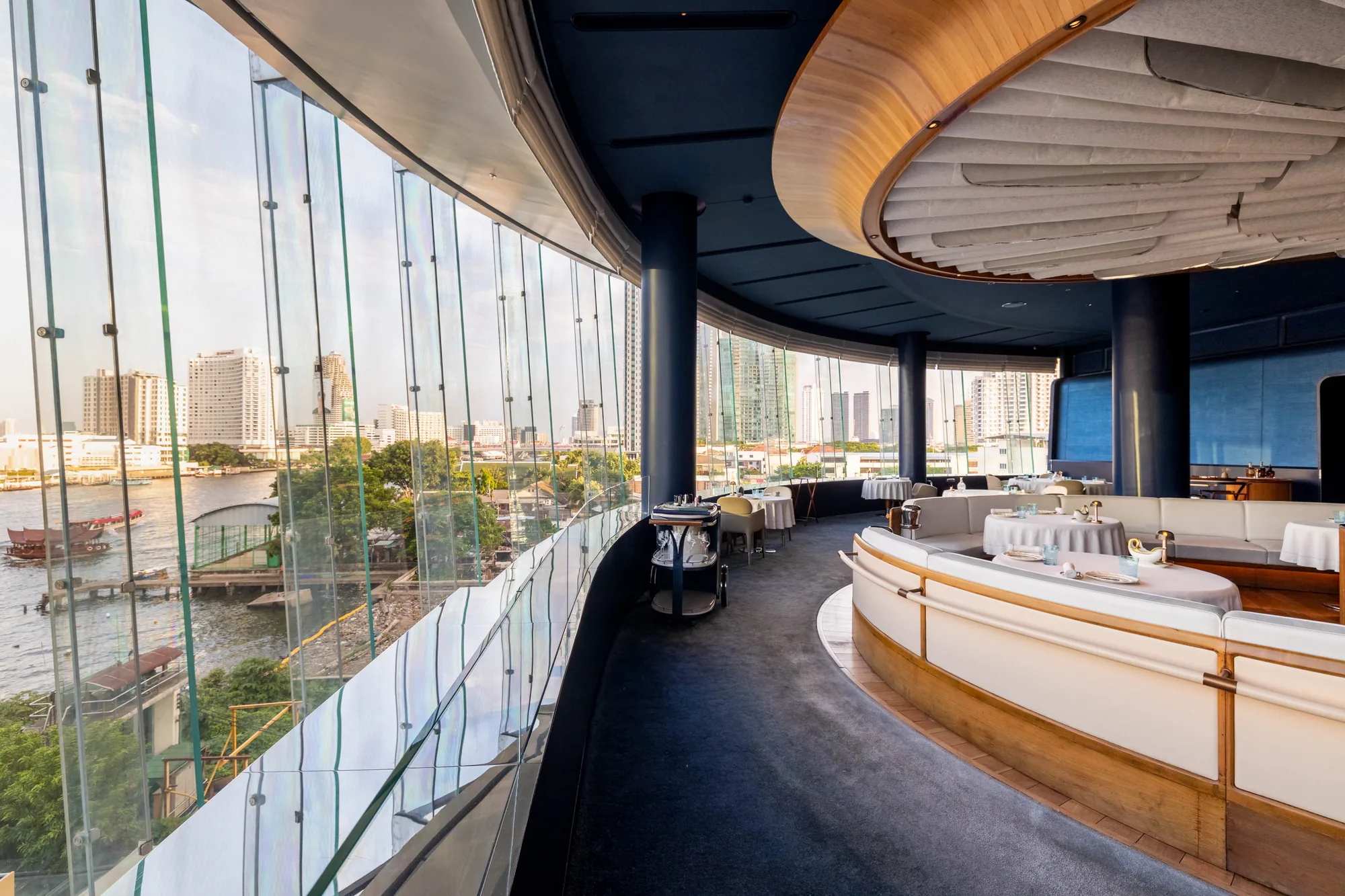 BLUE’s curved glass façade overlooking the Chao Phraya River.