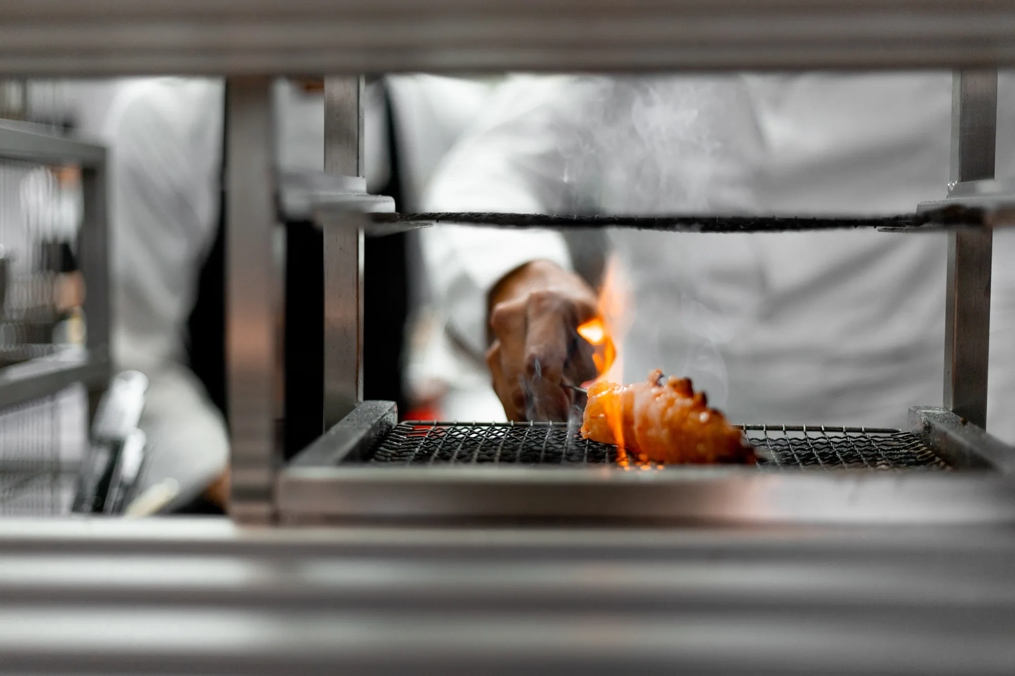 A BLUE chef finishing lobster over flame.