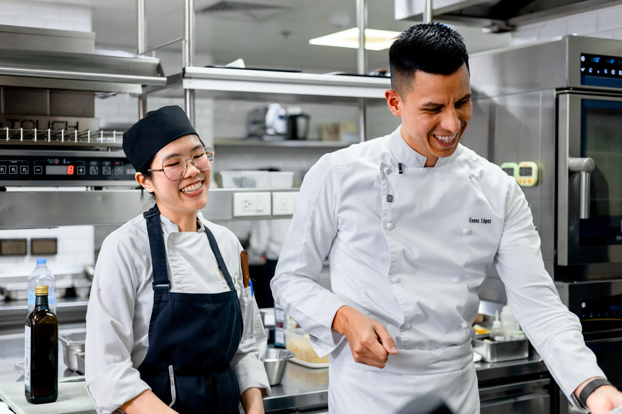 Two BLUE chefs smiling together in the kitchen.