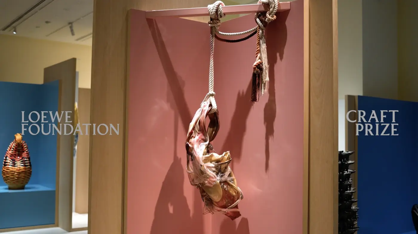 Faun’s Flesh by Maria Koshenkova, a glass sculpture hung from rope on a pink wall at the LOEWE FOUNDATION Craft Prize exhibition