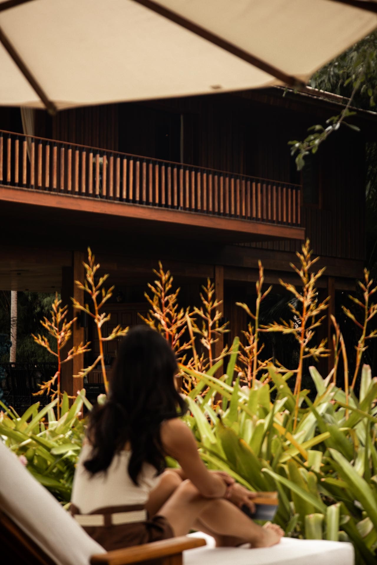 A guest relaxing beside tropical planting and Tatvani’s timber architecture.
