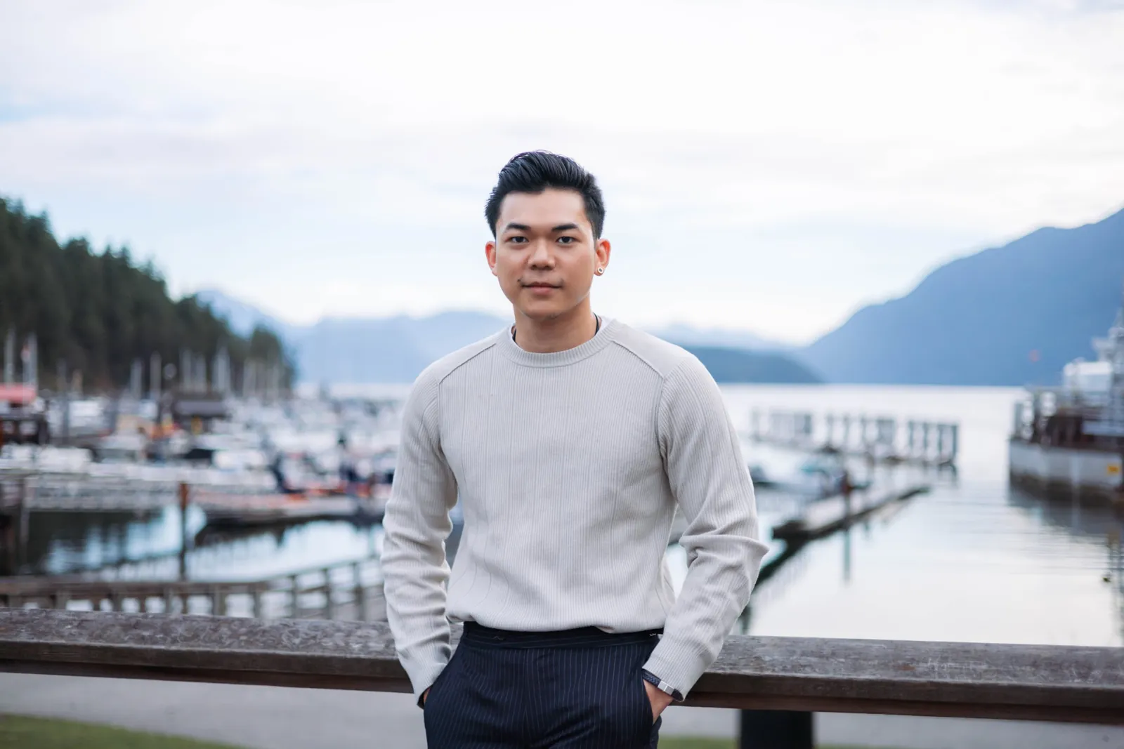 Deejai Riangkrul in a light sweater beside a marina with mountains in the background.