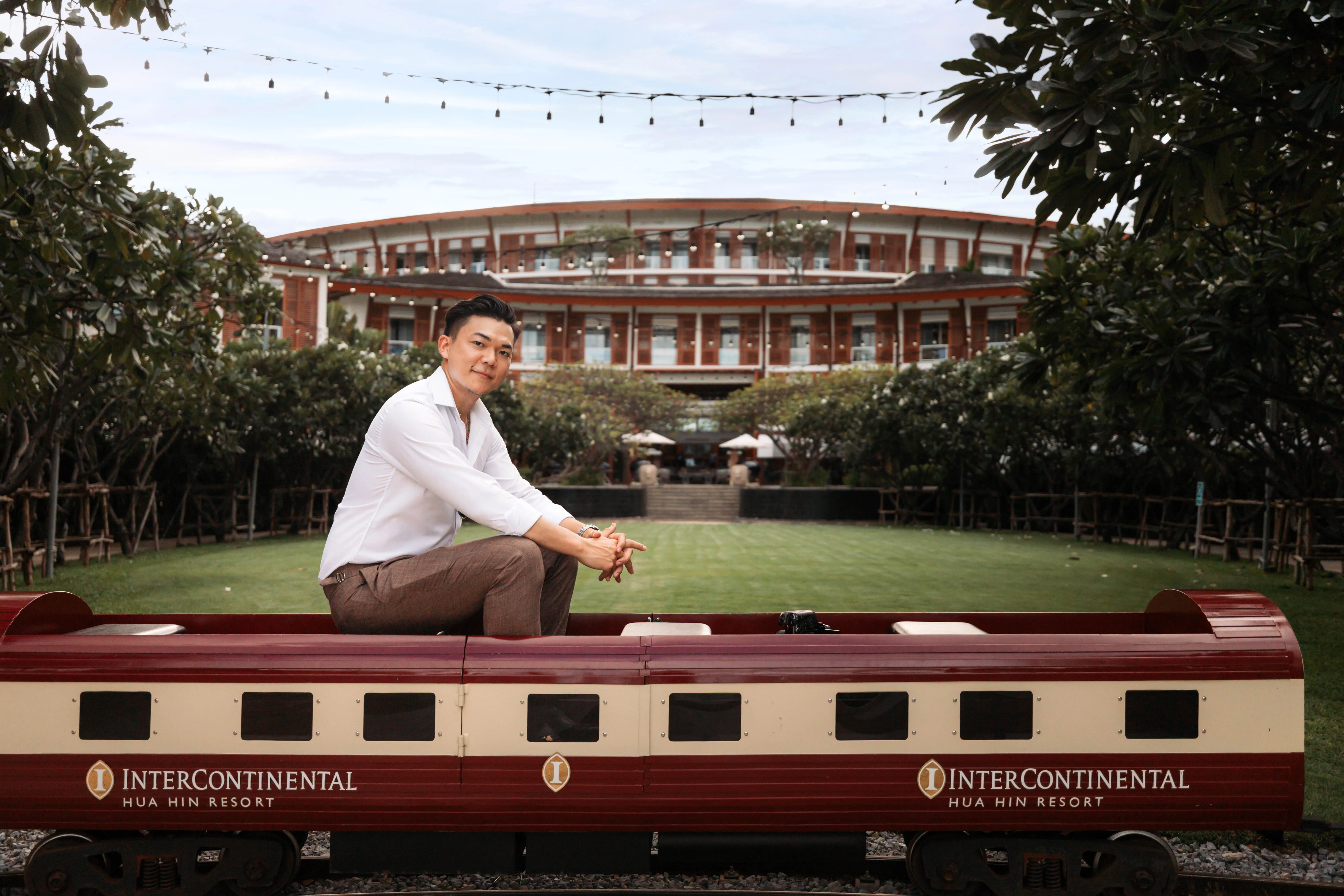 A guest seated on the resort's miniature train, with the InterContinental Hua Hin Resort building behind