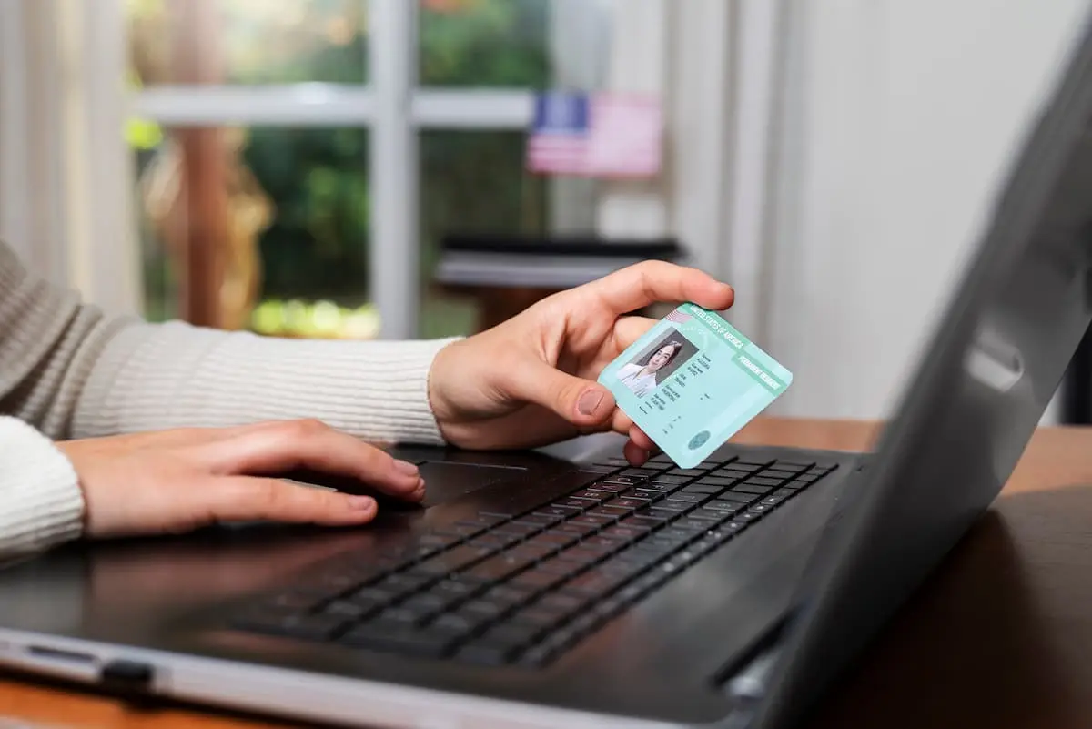 A woman with ID card in left hand works on a laptop