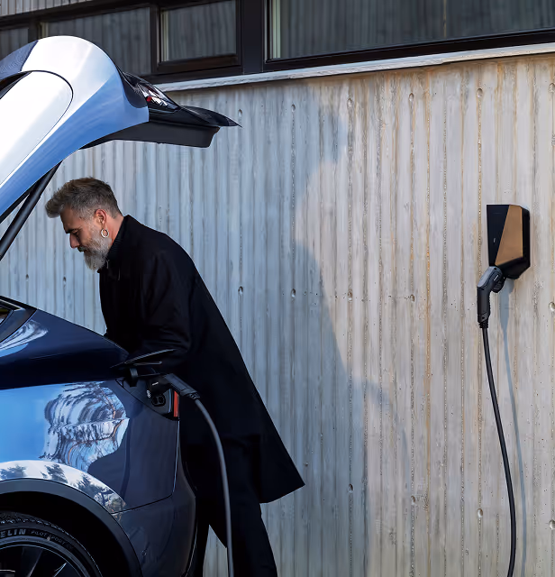 man charging his car while going through the trunk