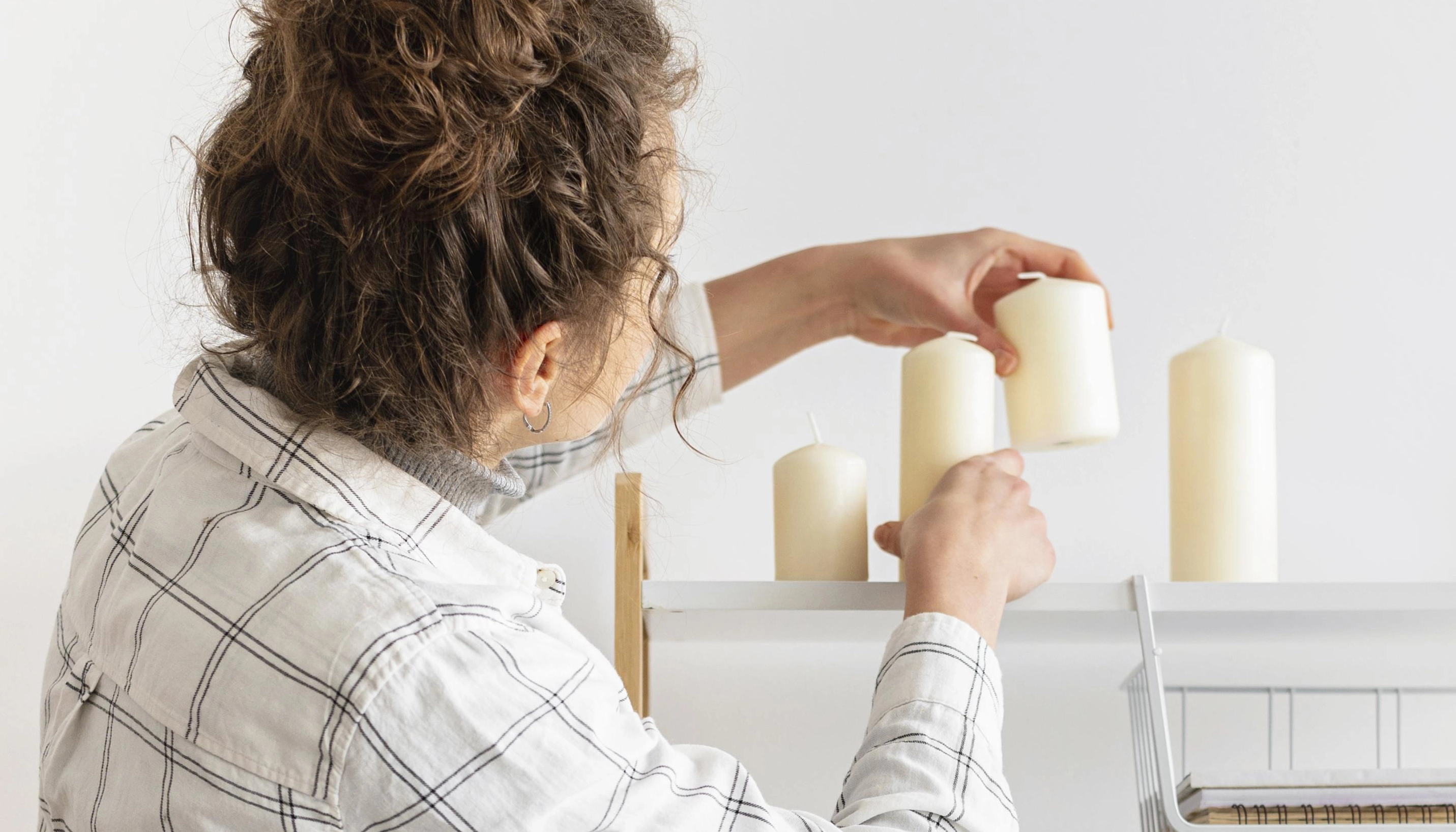 woman arranging her white candles on a shelf