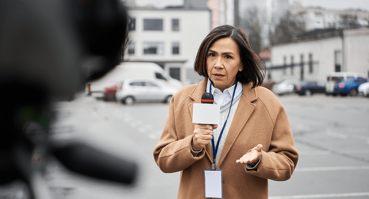 A woman holding a mic and reporting.