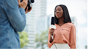 A picture of a Lady reporting with the camera man