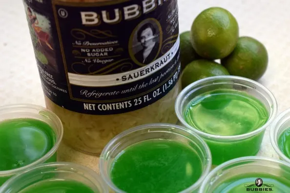 cups of boozy jello with jar of Sauerkraut and limes