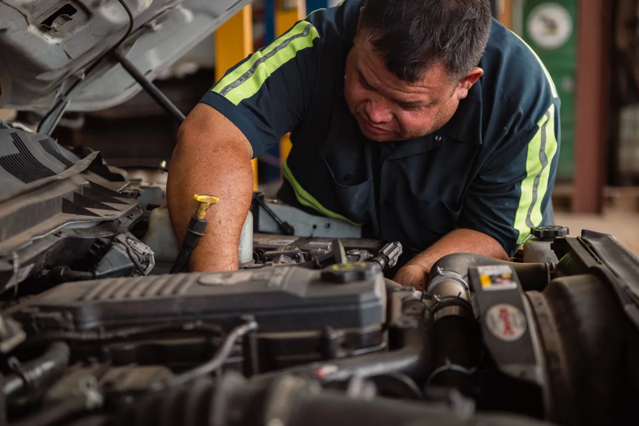Mechanic performing engine repair on a heavy-duty truck, inspecting components under the hood.