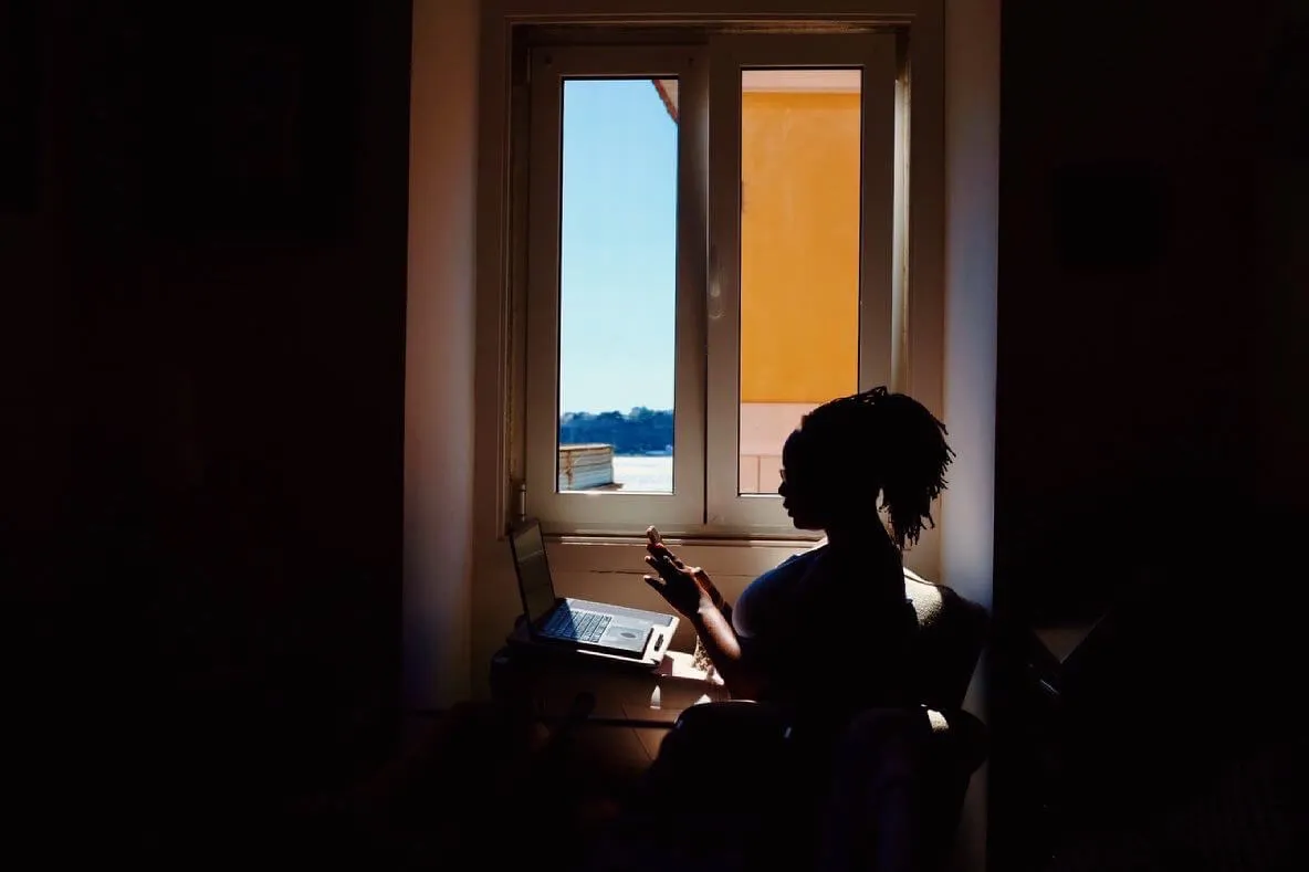 a person sitting at a desk with a laptop and a phone