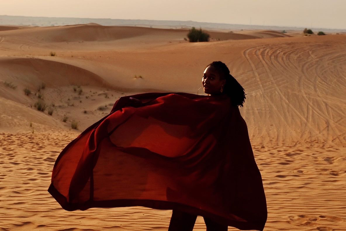 a woman wearing a dark red robe in the desert
