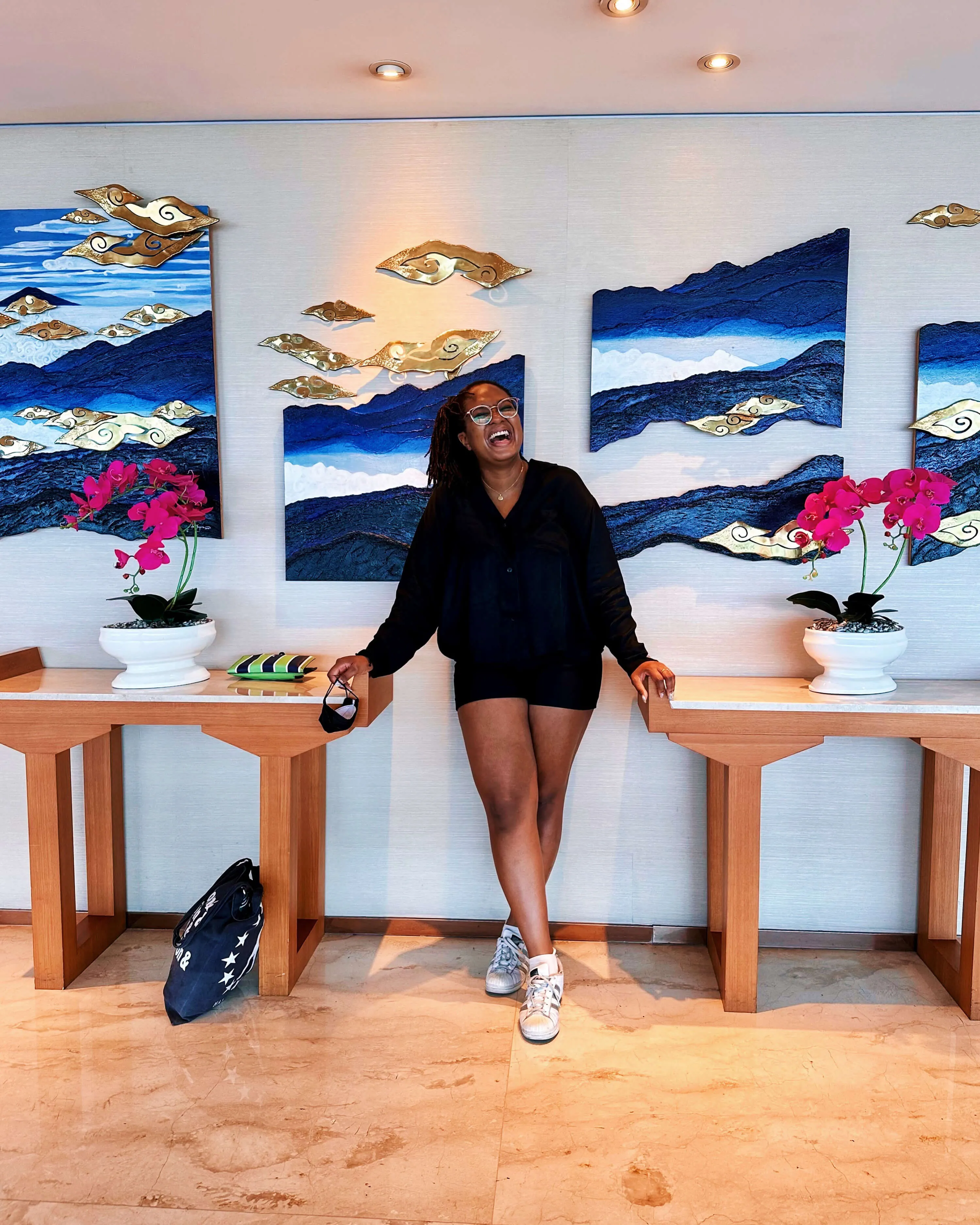 a woman standing in-between two tables laughing at the camera