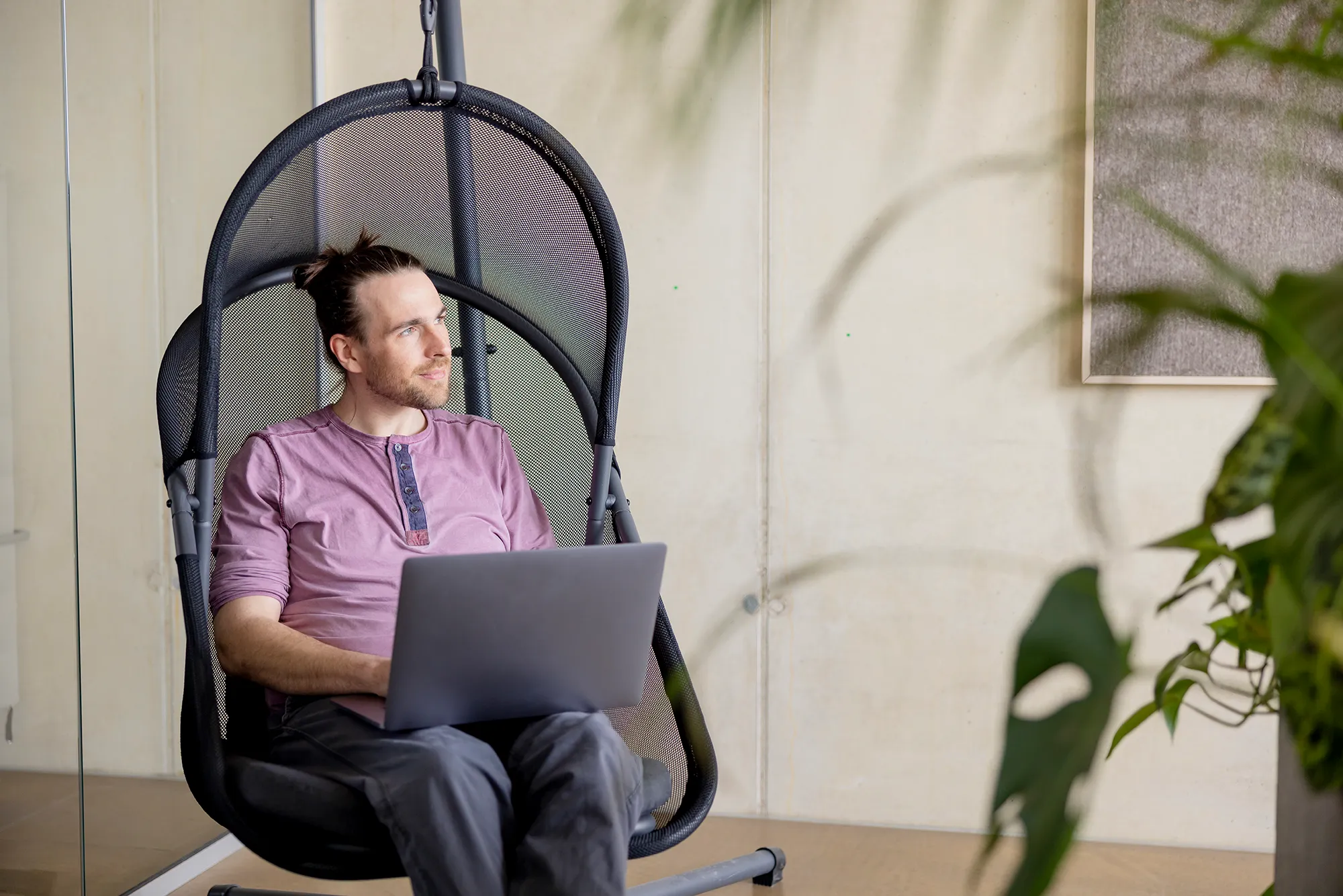 Ein Entwickler arbeitet zur Abwechslung im Hängesessel in unseren modernen Büros.