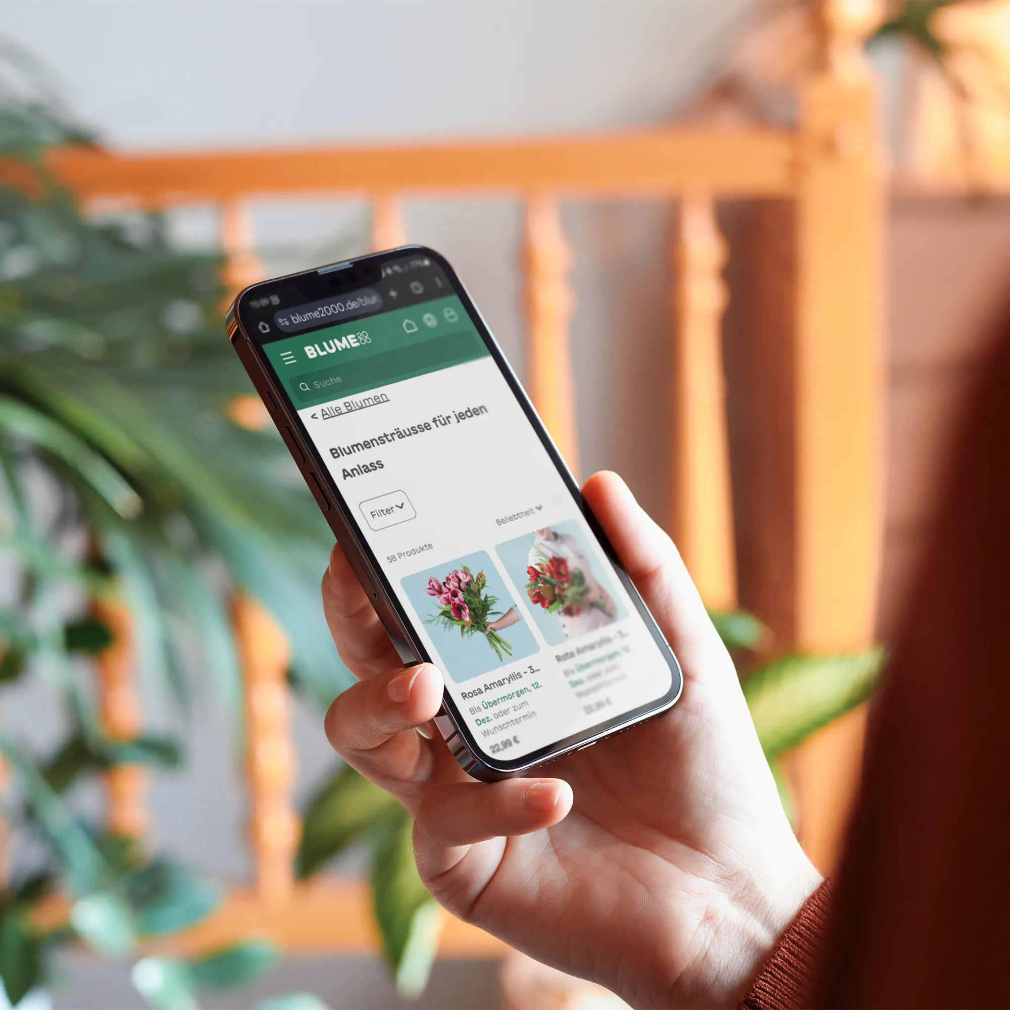 Person schaut sich die Website von BLUME2000 auf dem Smartphone an.