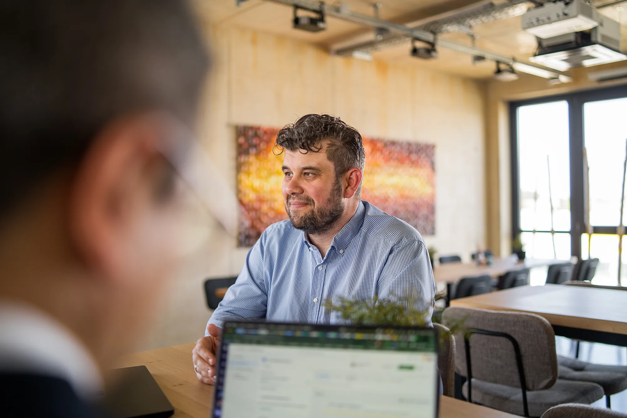 Mitarbeitender sitzt am Tisch mit Kunden.