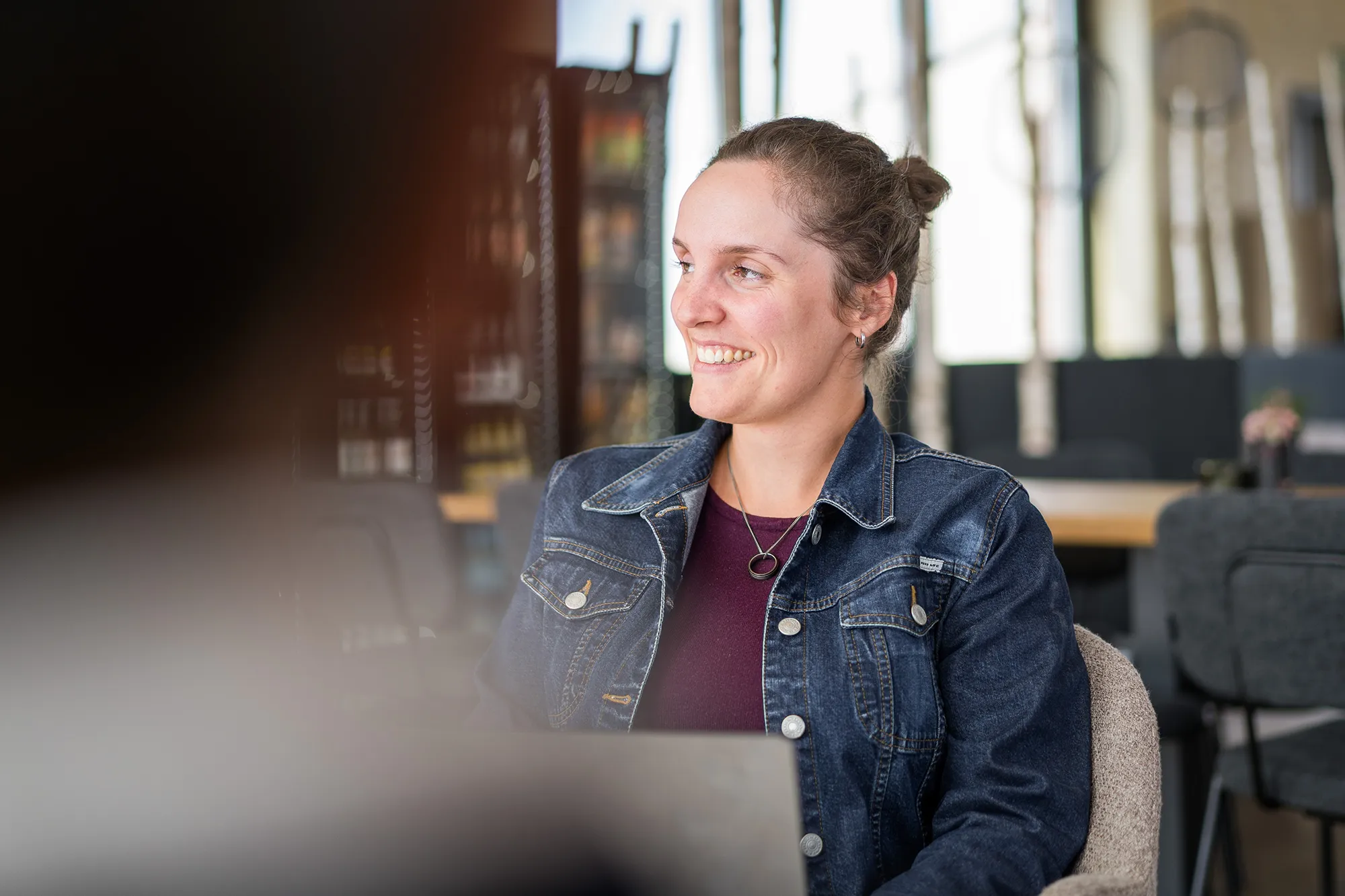 Mitarbeitende sitzt im Büro und hört gespannt zu.