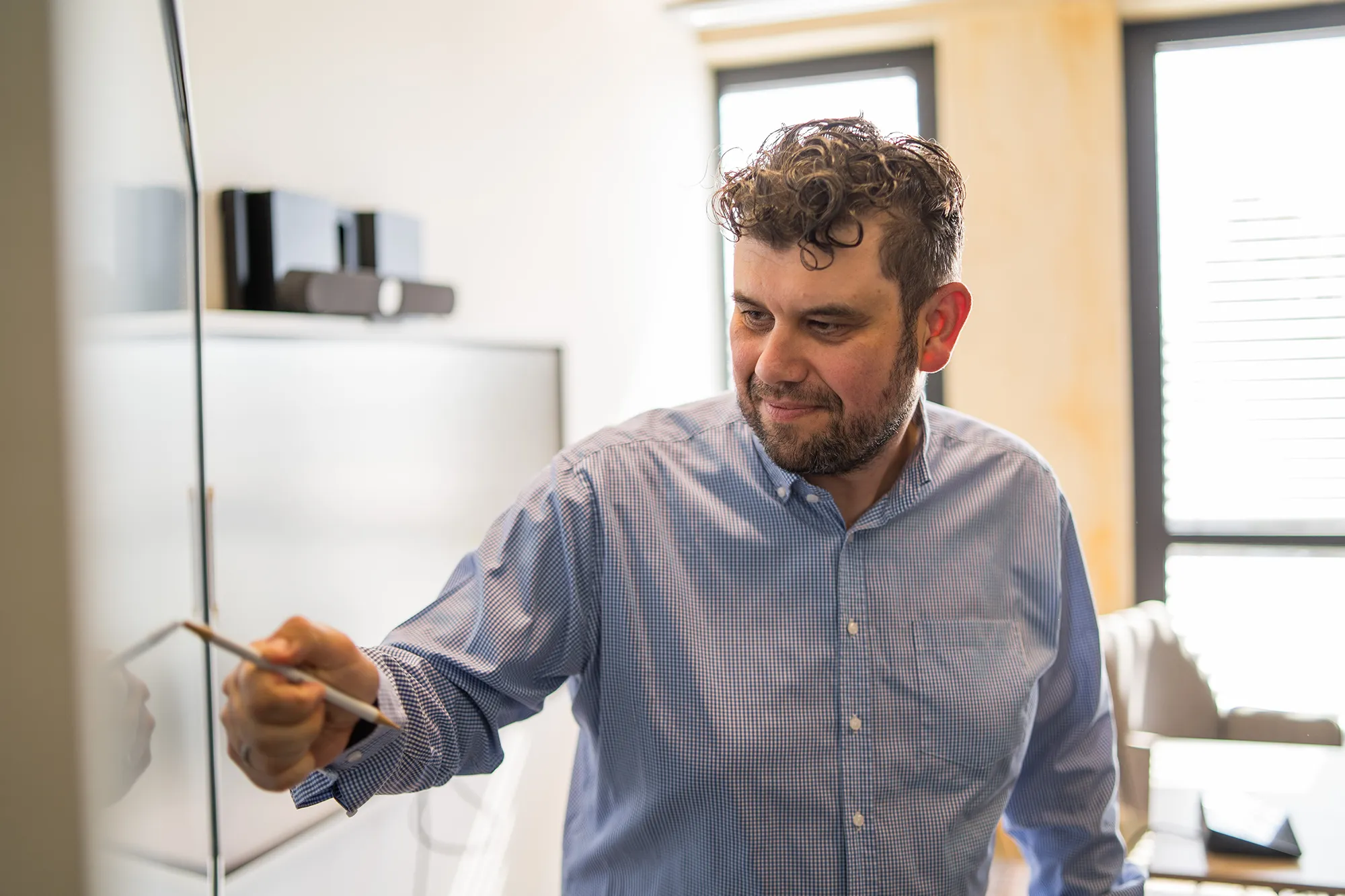 Mitarbeitender zeigt etwas auf dem Whiteboard.