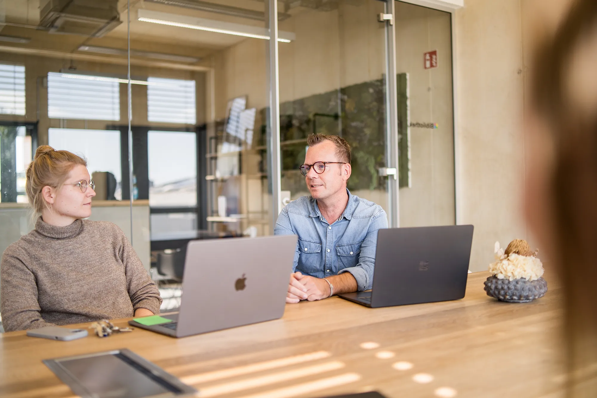 Zwei Mitarbeitende besprechen sich am Meeting-Tisch.