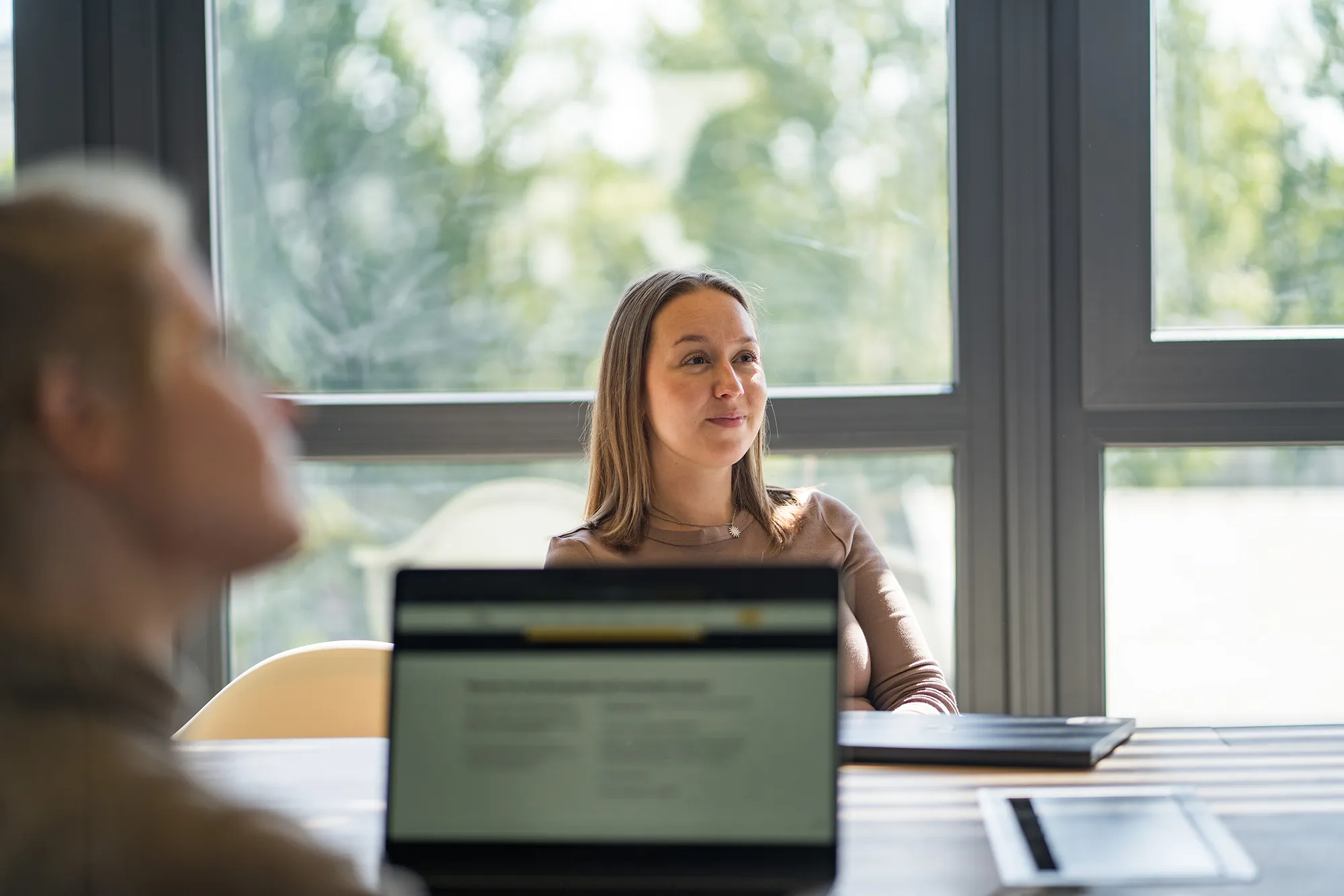 Zwei Arbeitskolleginnen schauen interessiert in Richtung Whiteboard.