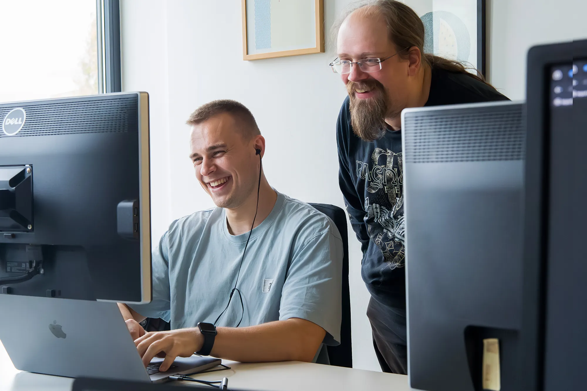 Zwei Kollegen schauen gemeinsam auf den Monitor im Büro.