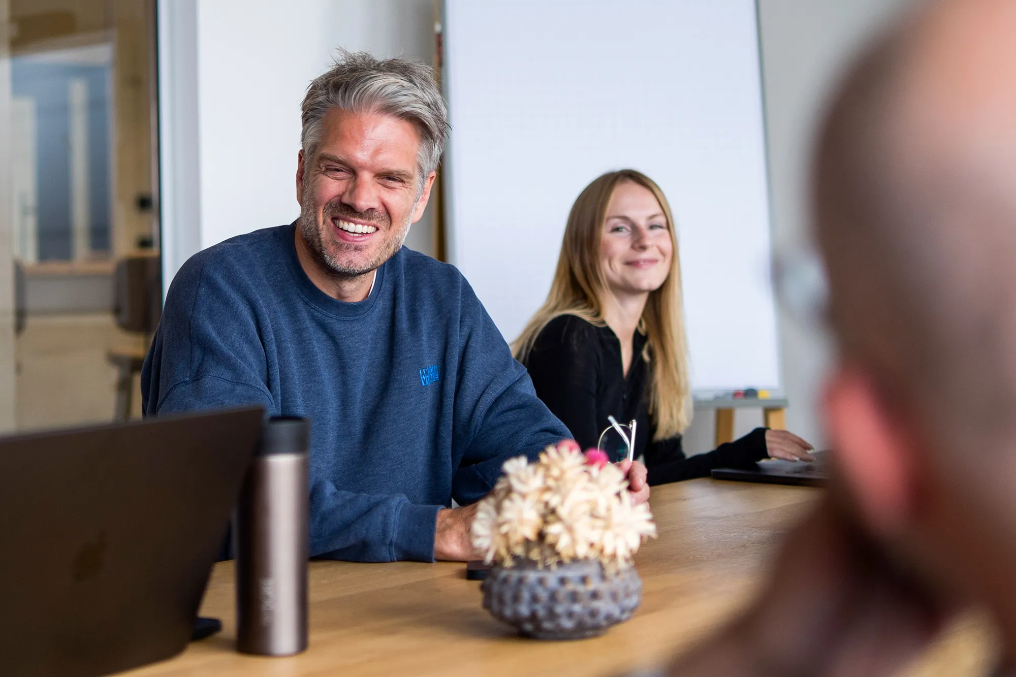 Zwei Mitarbeitende sitzen freudig im Meeting