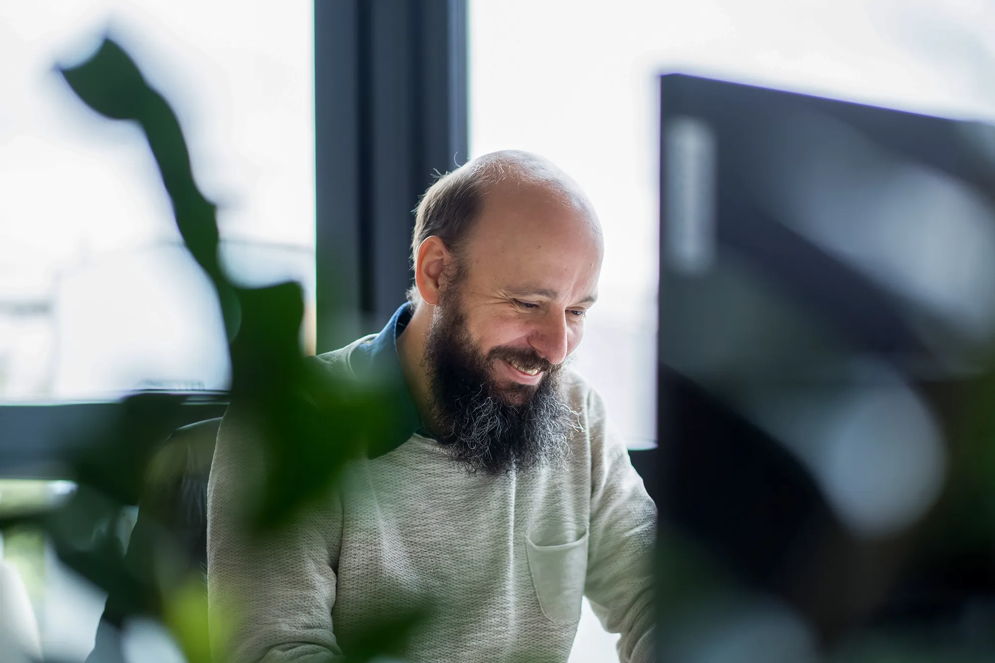 Mitarbeitender schaut freudig auf seinen PC