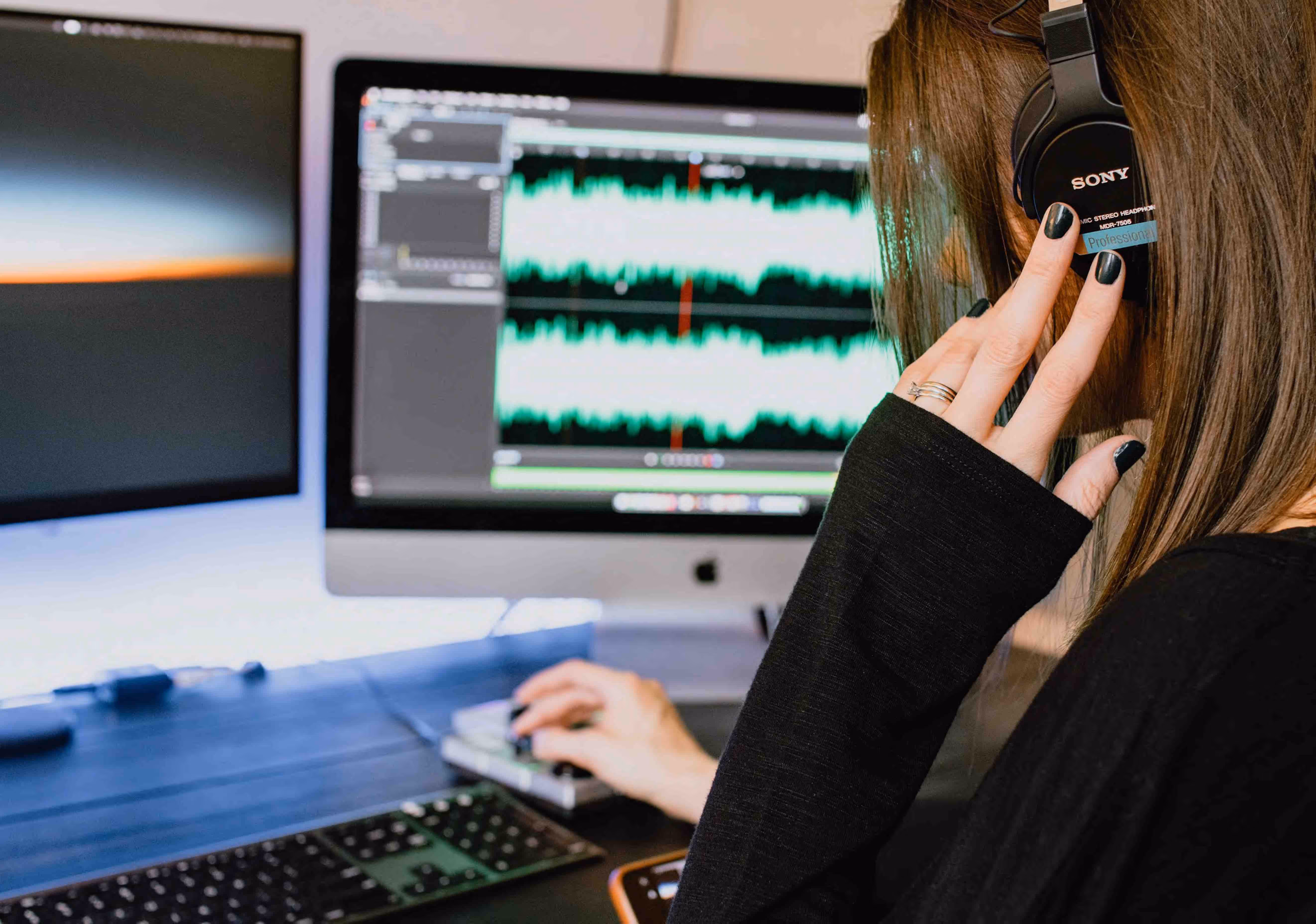 A woman editing audio with headphones on