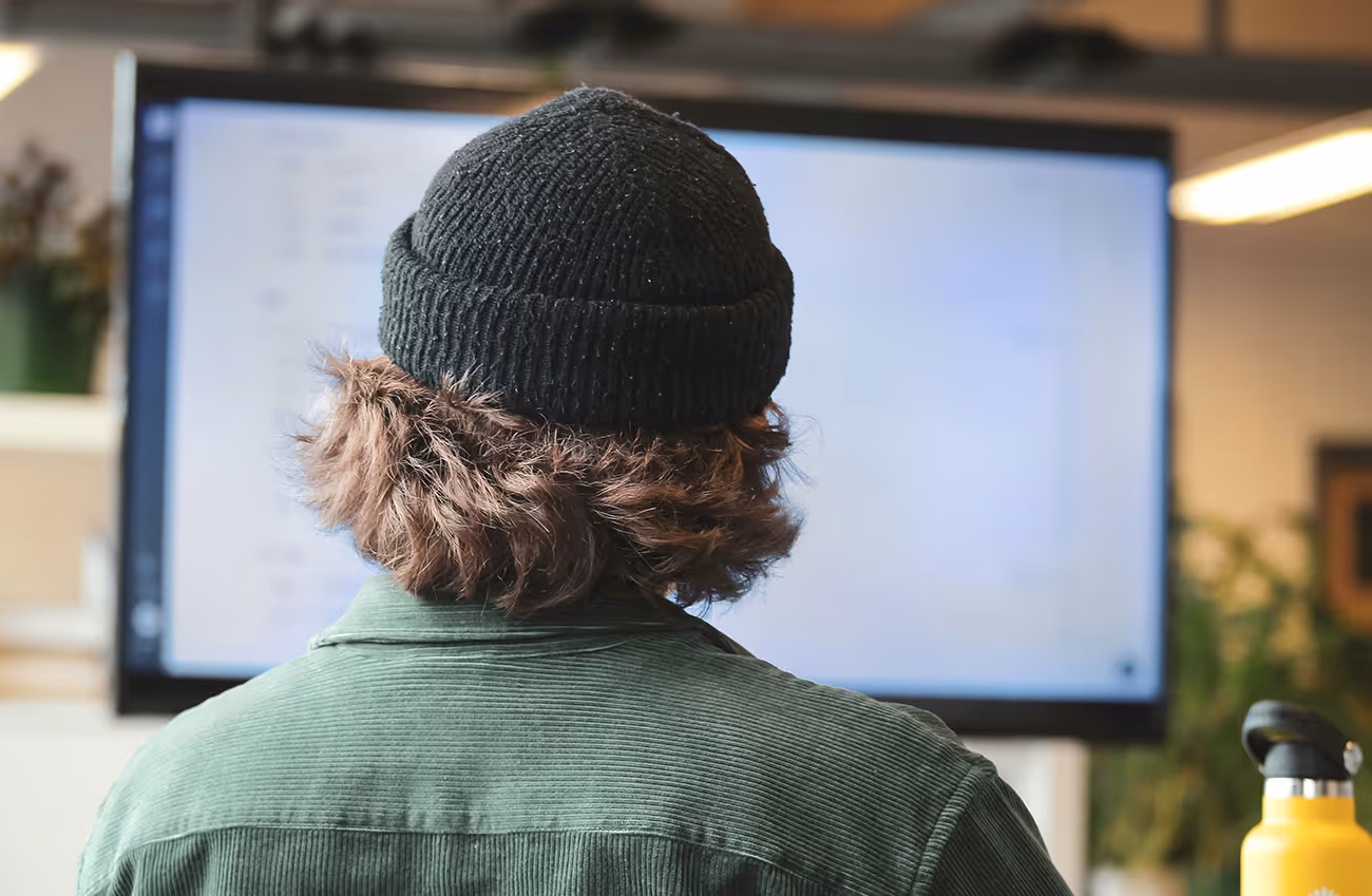 Image shows the back of a man looking up a large computer screen.