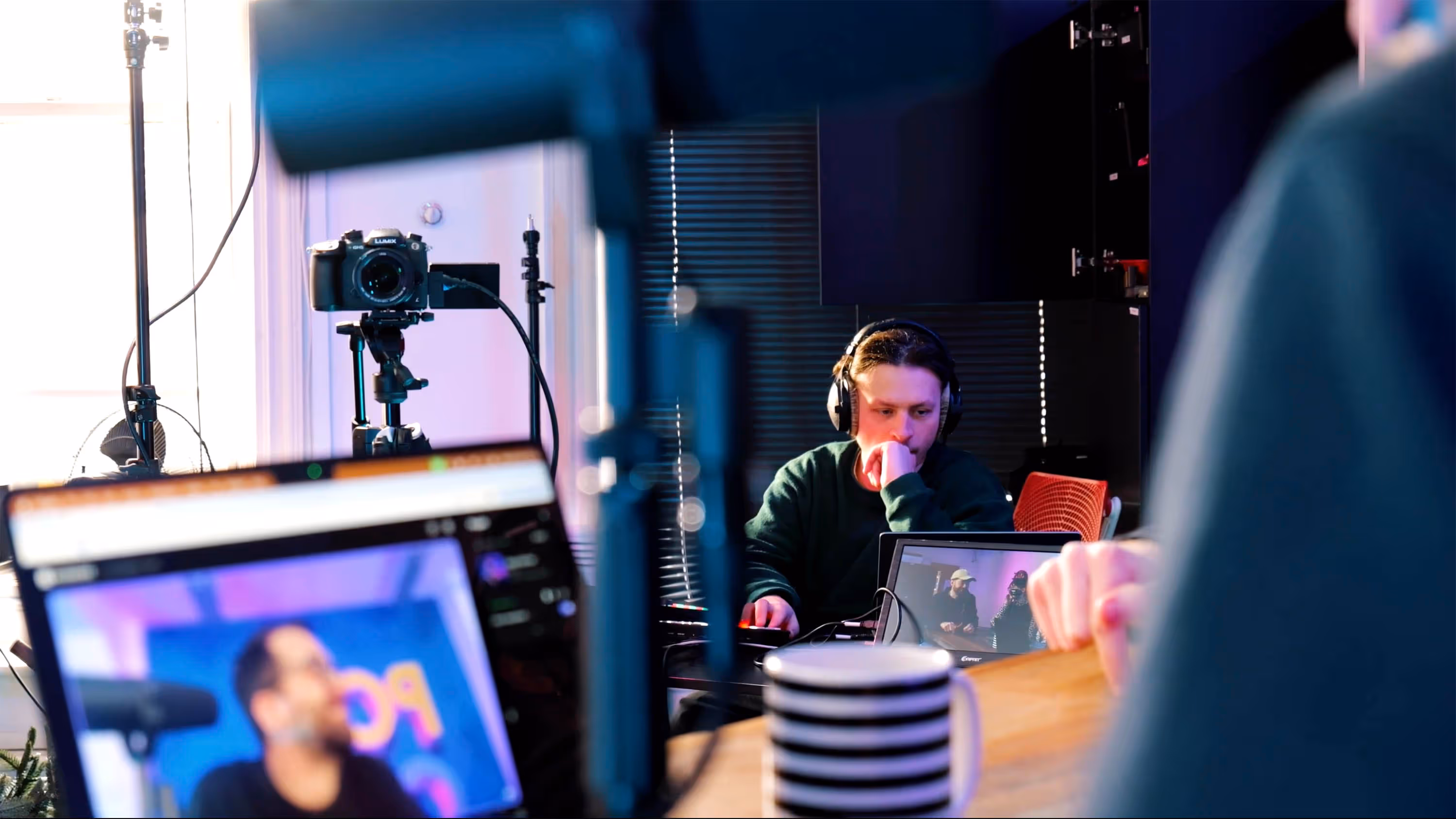 studio setting with camera equipment and laptop screens. man with headphones producing a video.