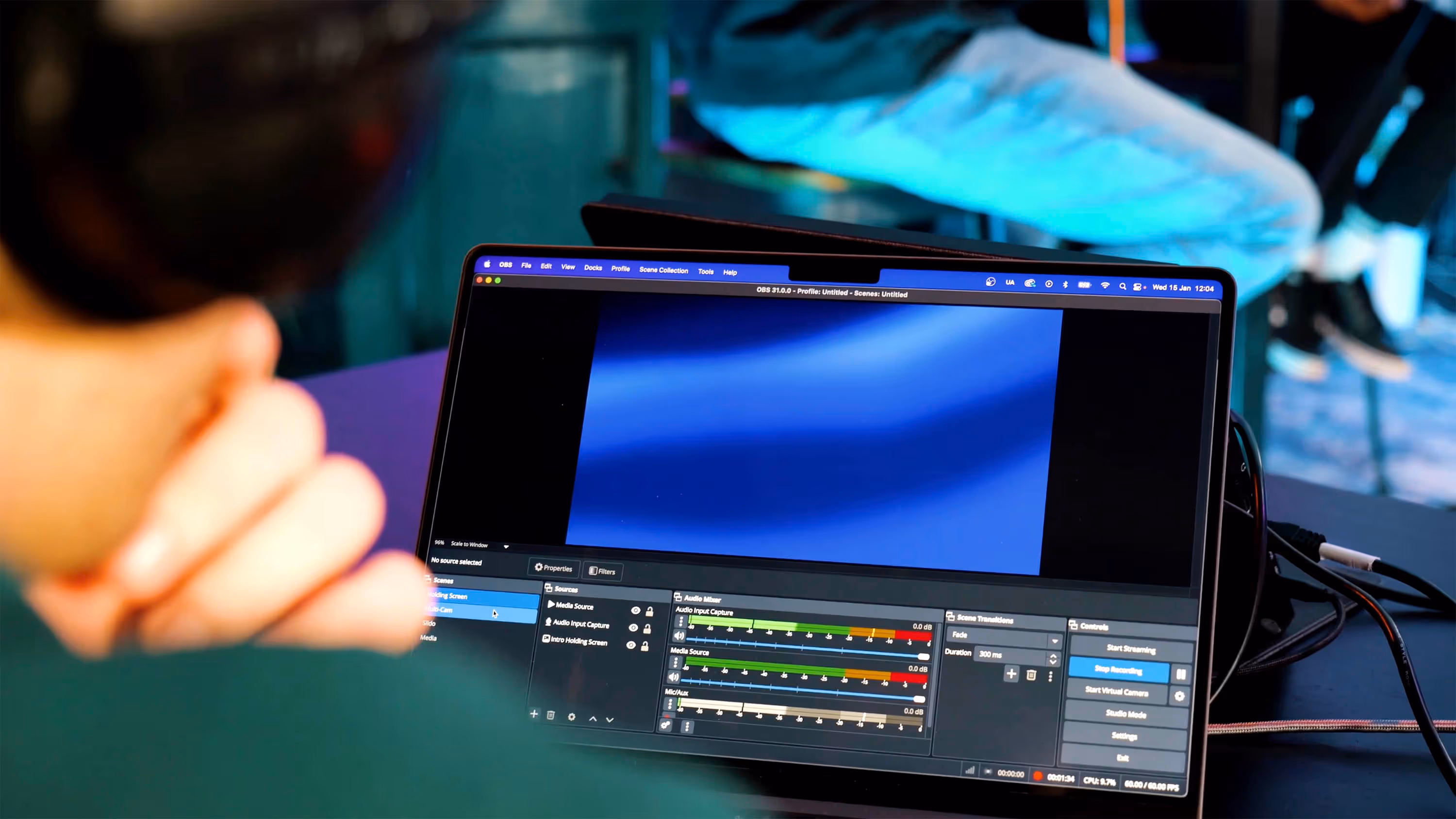 out of focus person looking at a laptop screen utilising a video and audio production editing software