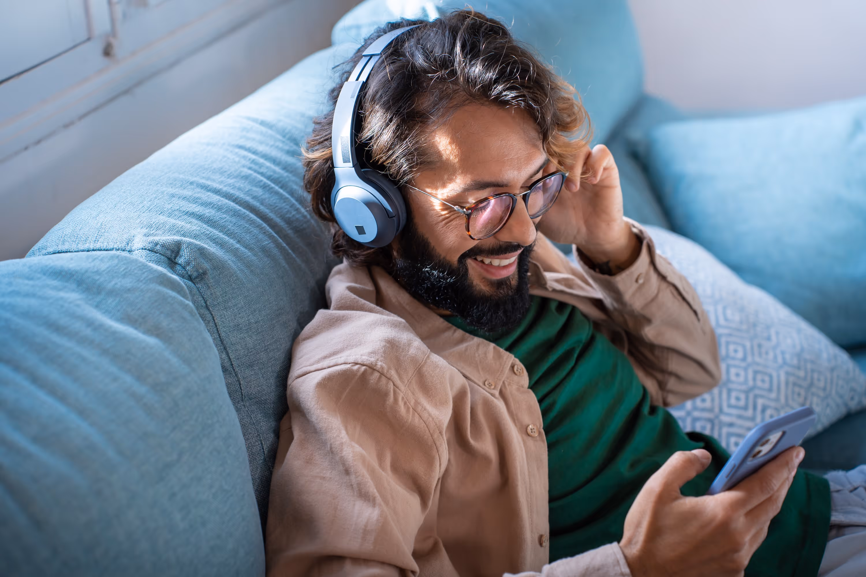 Smiling man with headphones on looking at his phone